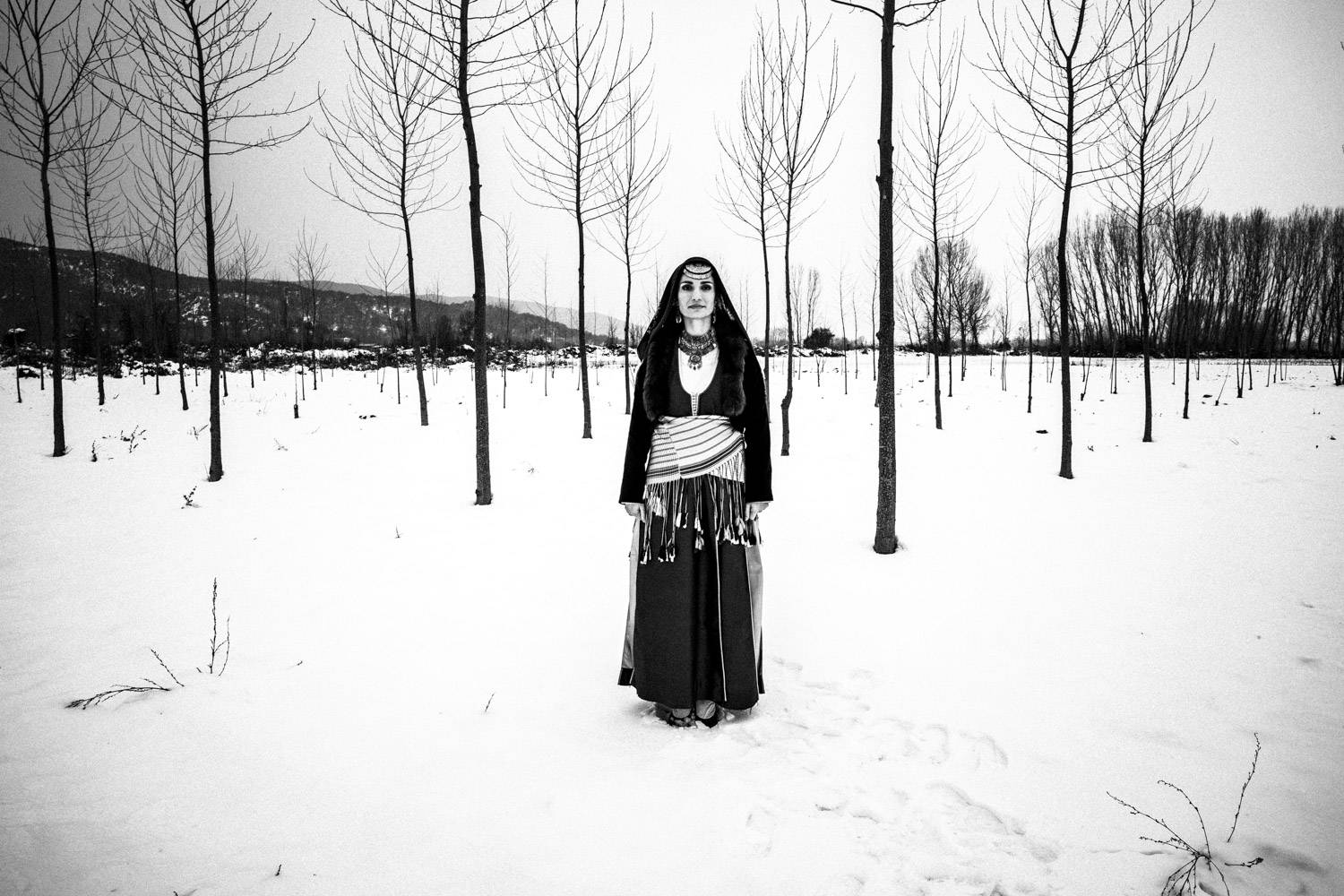 A woman wearing the traditional Pontic costume, posing on the frozen lake Kerkini, Macedonia, Greece. Black and white photograph by George Tatakis