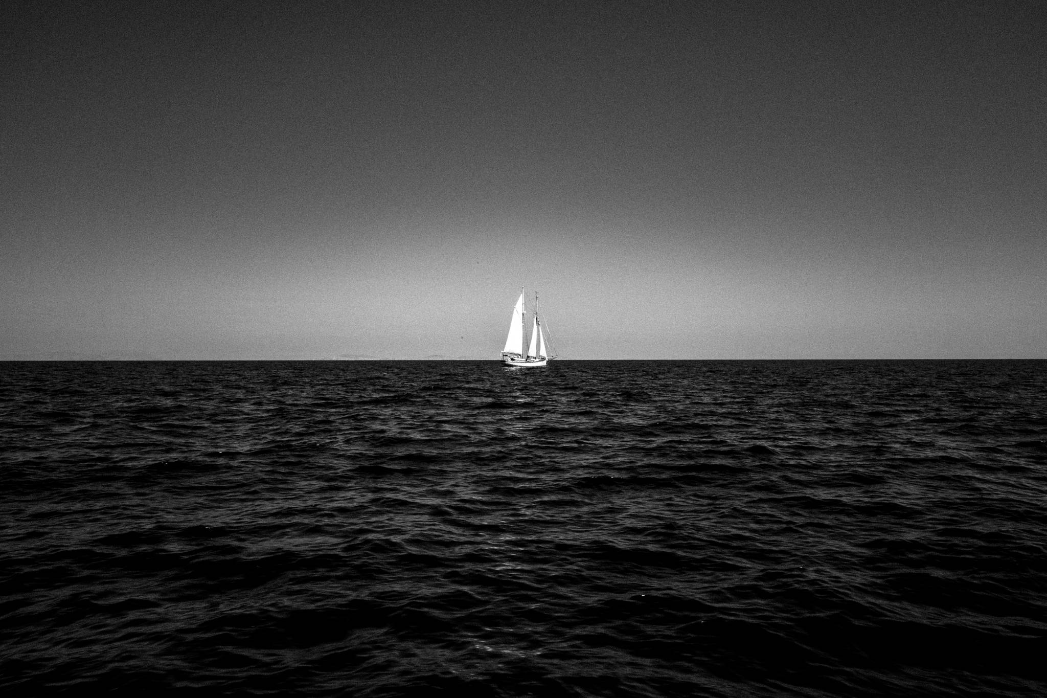 A small sailboat soaring the sea, by photographer George Tatakis