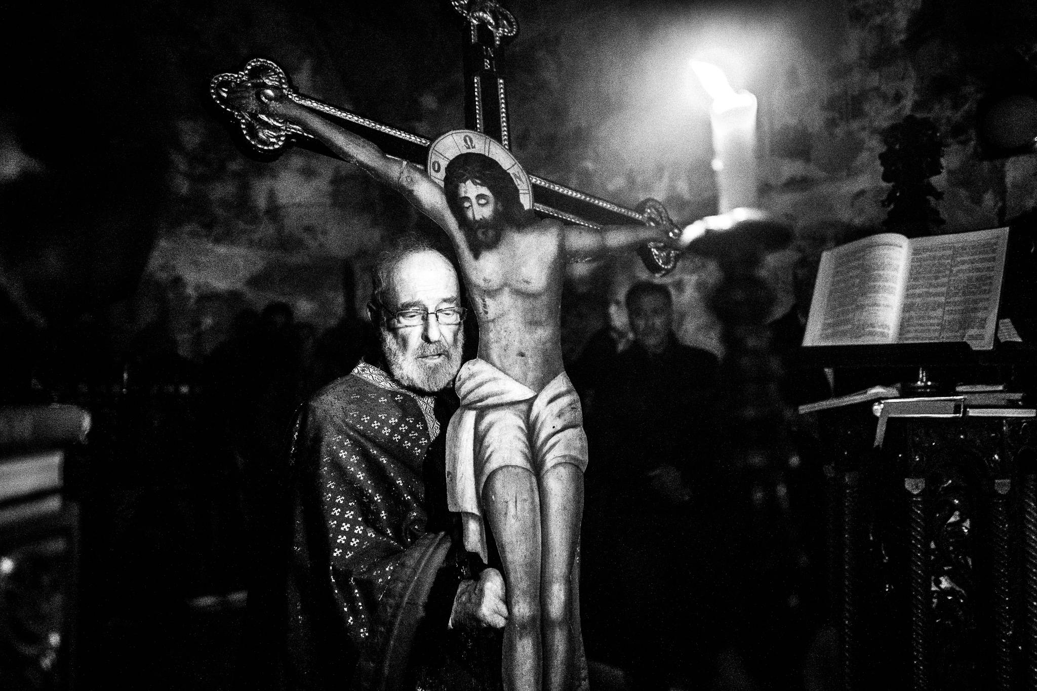 The local priest, carrying the cross on Holy Thursday, inside the main church. Olympos, Karpathos, Greece