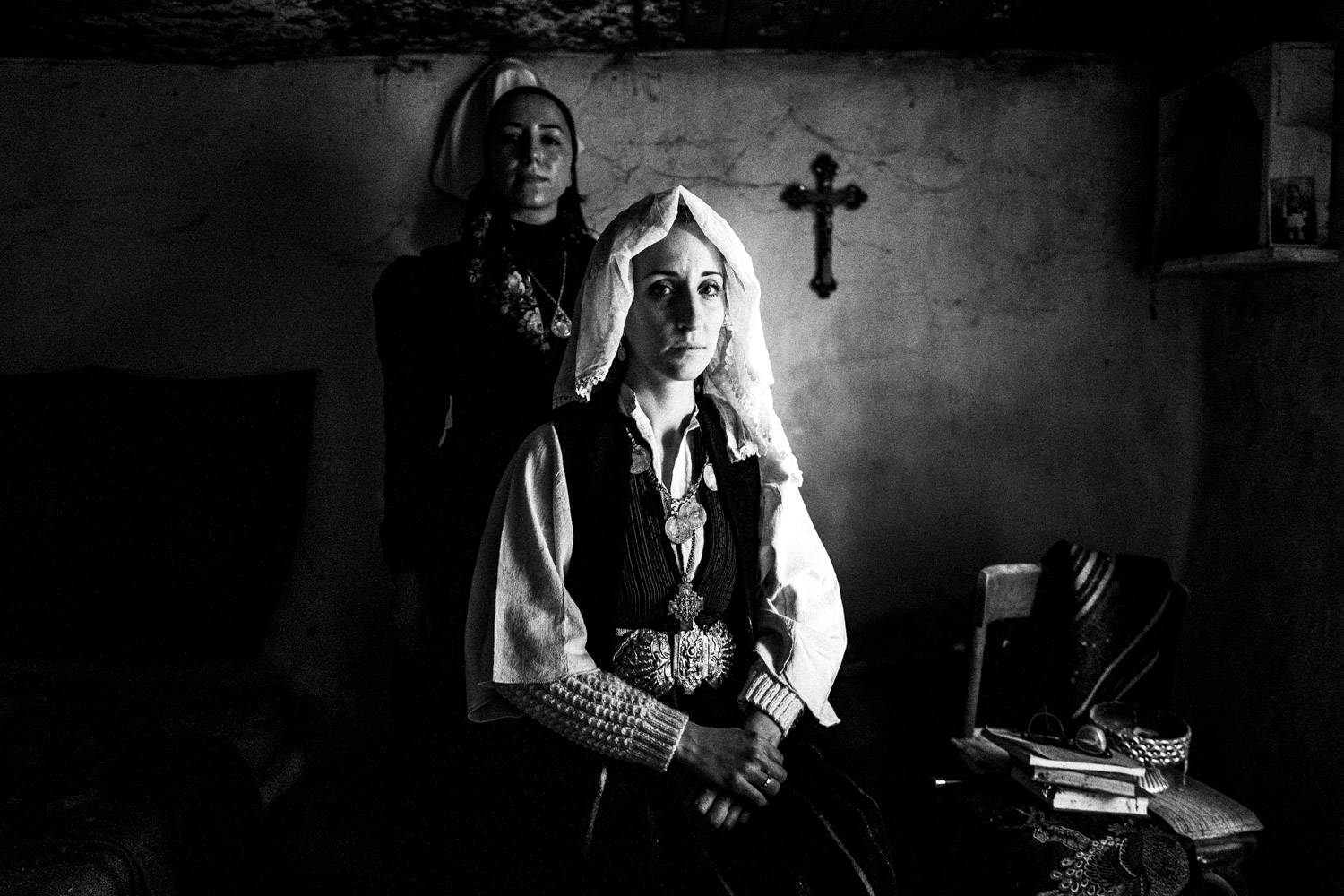 Portrait of a bride with her friend in their traditional attires at an abandoned house. Ermakia, Ptolemaida, Macedonia, Greece. Black and white photograph by George Tatakis