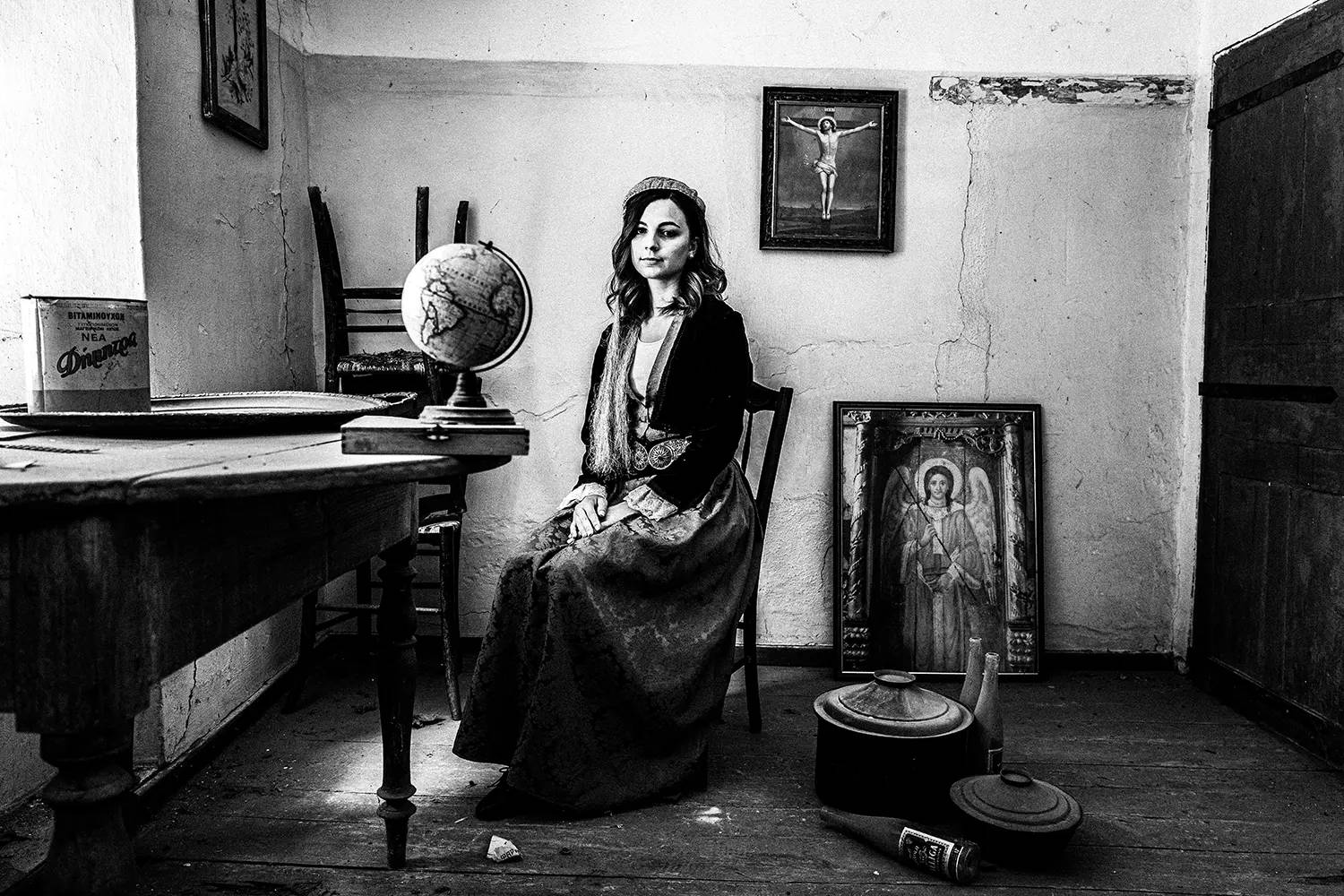 A woman inside an old house in Pinakates, wearing the folklore dress of Pelion, Thessaly, Greece. Black and white photography by George Tatakis