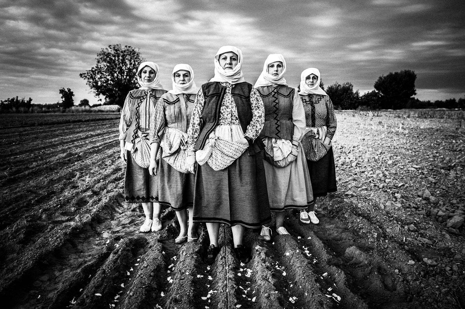 Women wearing the traditional costumes in a garlic field. Vyssa, Evros, Greece.