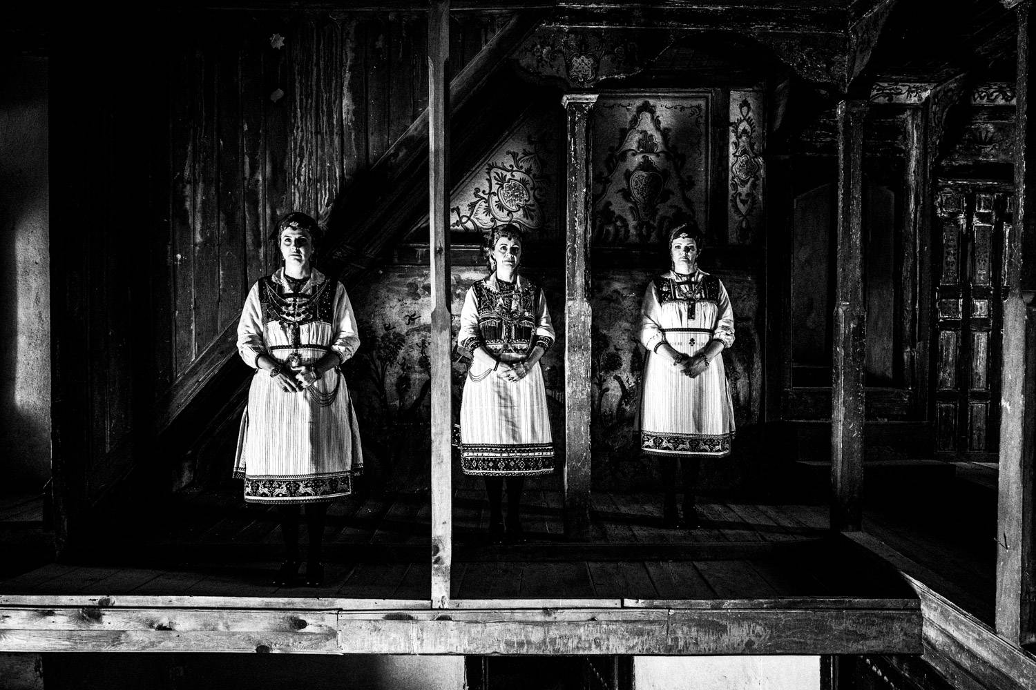Three women standing inside a Mansion in Siatista, wearing the folklore dresses of Tsartsampas. Macedonia, Greece. Black and white photograph by George Tatakis