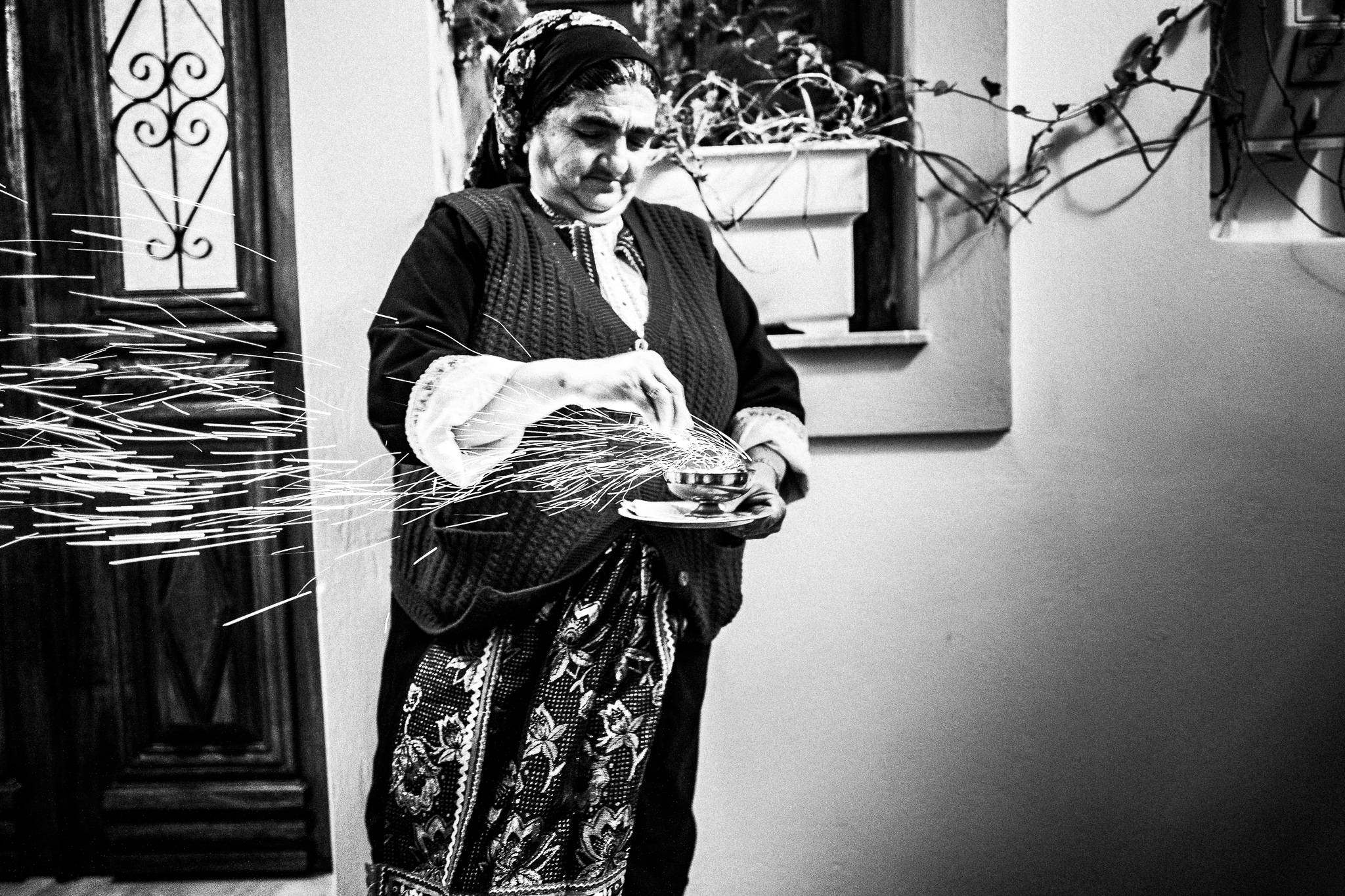 A woman in her traditional costume, lighting a cencer on Good Friday. Olympos, Karpathos, Greece