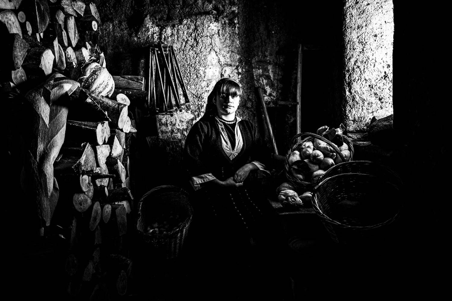 A woman wearing the folklore dress of Prespes inside an old warehouse, Macedonia, Greece. Black and white photograph by George Tatakis