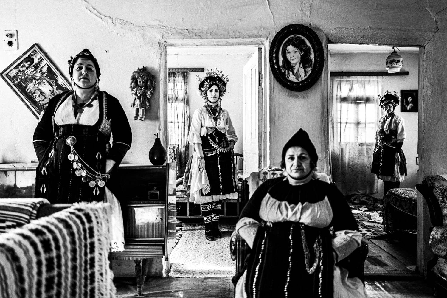 Four women wearing the Roumlouki costumes, inside an old local house. Meliki, Imathia, Macedonia, Greece. Black and white photograph by George Tatakis