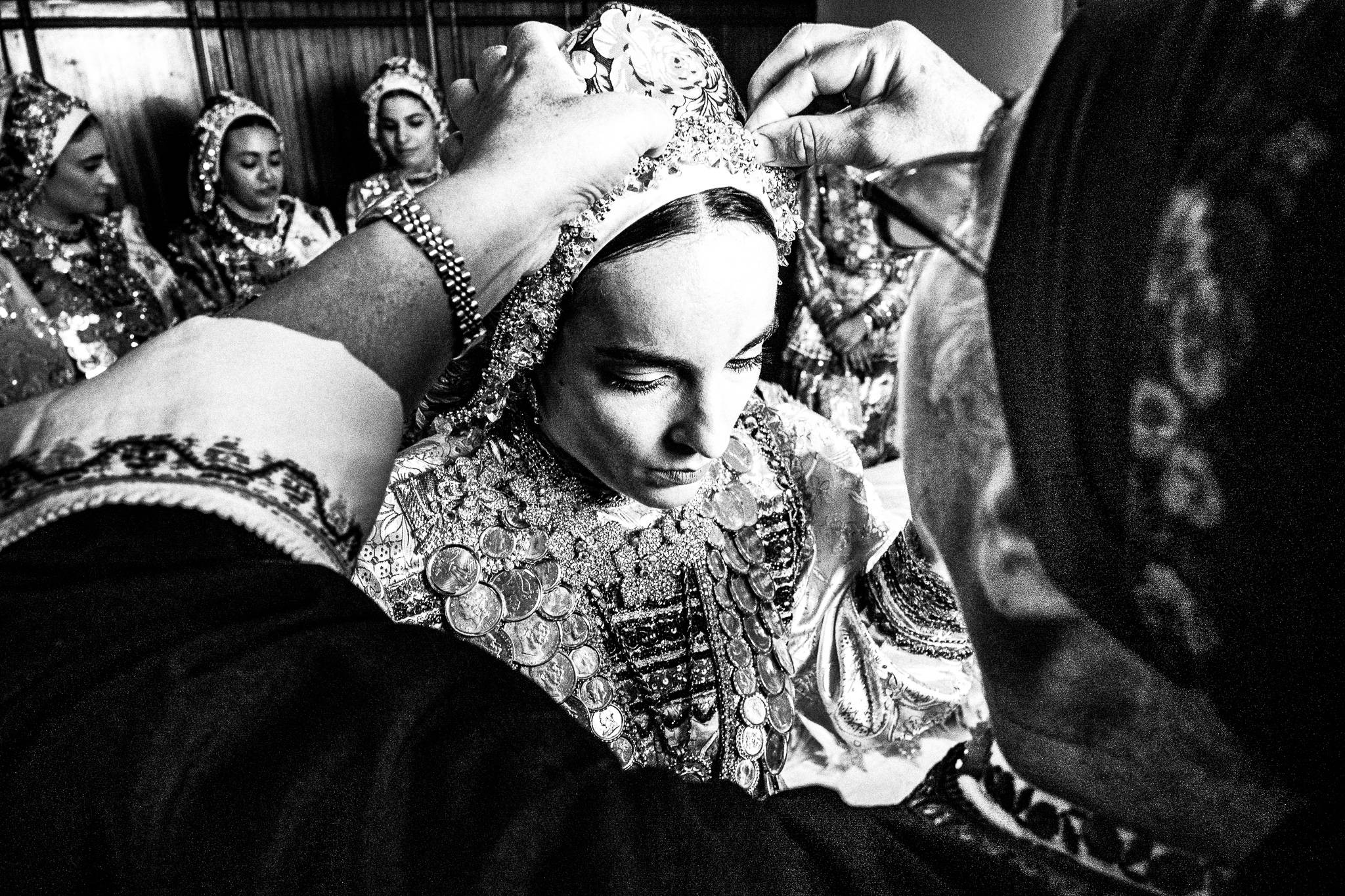 Fixing the jewelry at a traditional wedding at Olympos, Karpathos, Greece. Black and white photography by George Tatakis