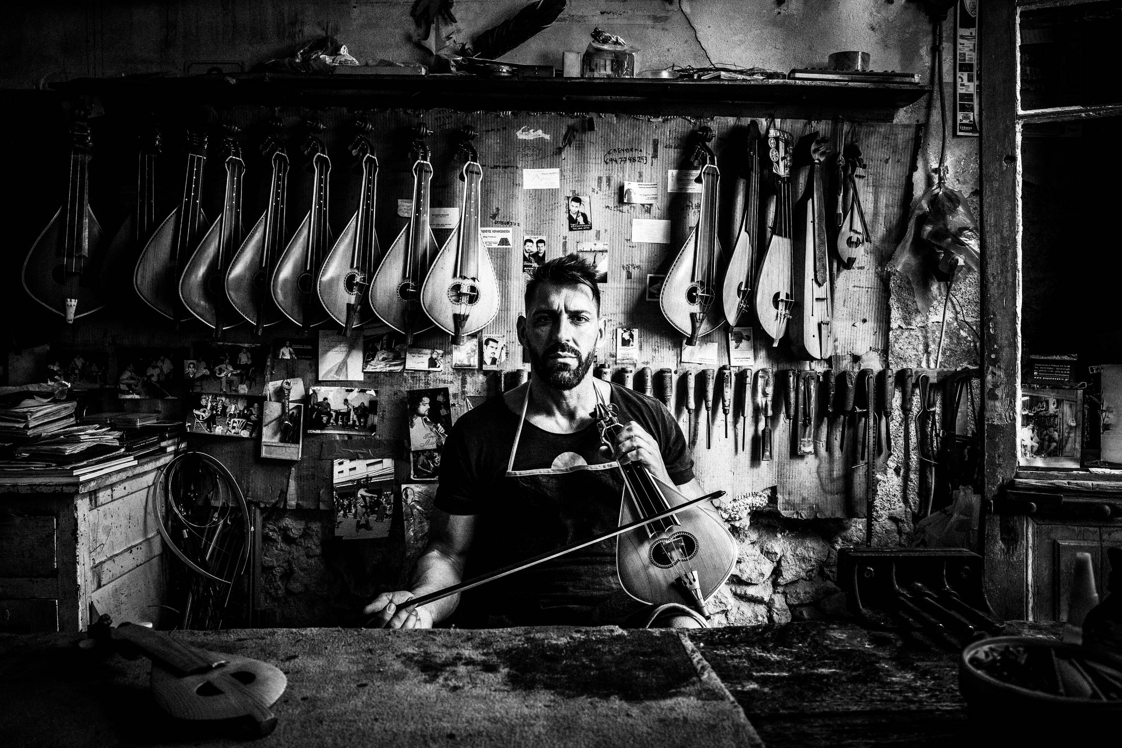 Nikos playing the lyre inside his workshop in Rethymnon, Crete, by photographer George Tatakis