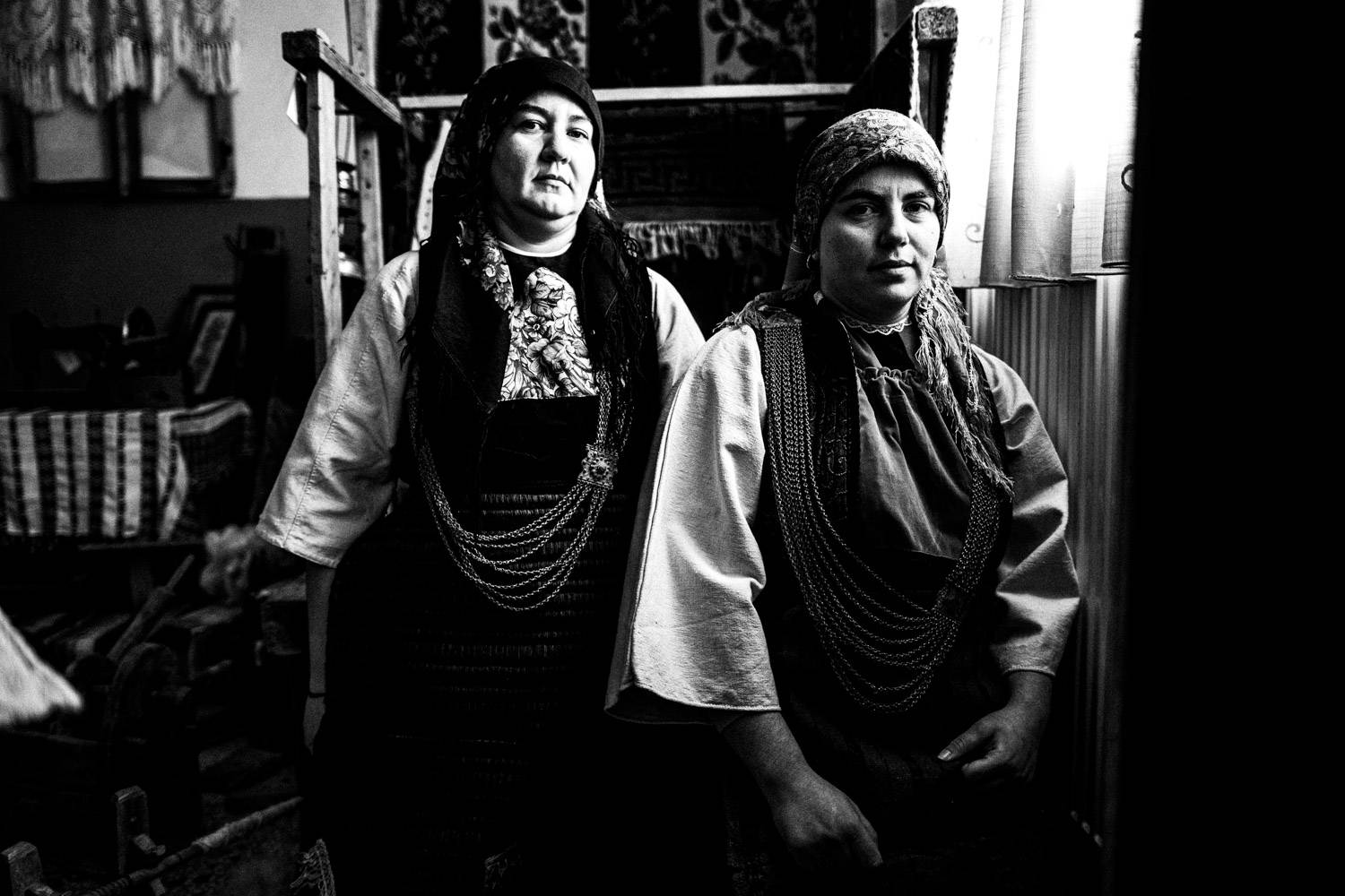 Two women in their local folklore dresses. Skopos, Florina, Macedonia, Greece. Black and white photograph by George Tatakis
