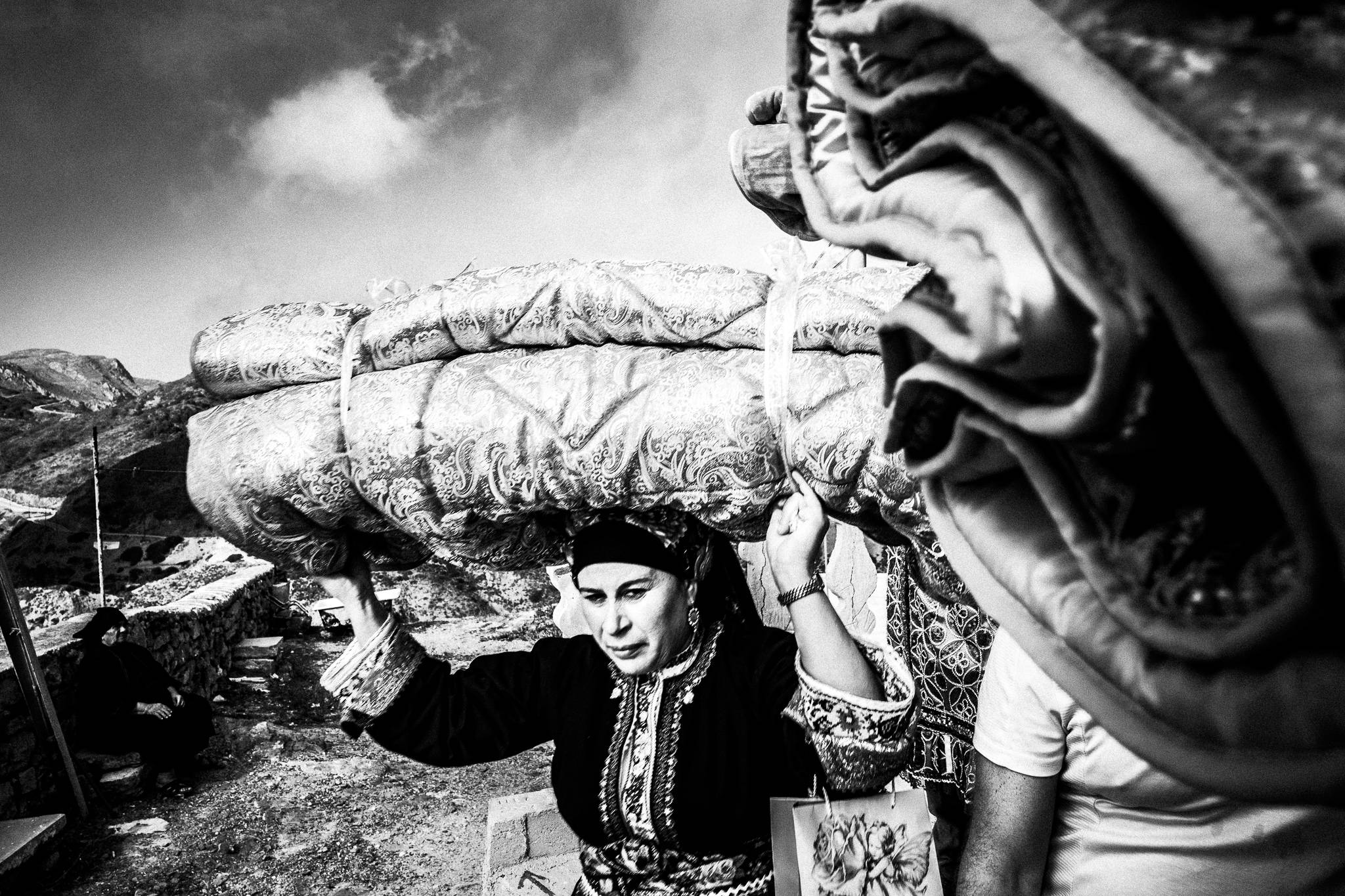 Carrying the dowry on the head at a wedding in Olympos, Karpathos, Greece. Black and white photography by George Tatakis