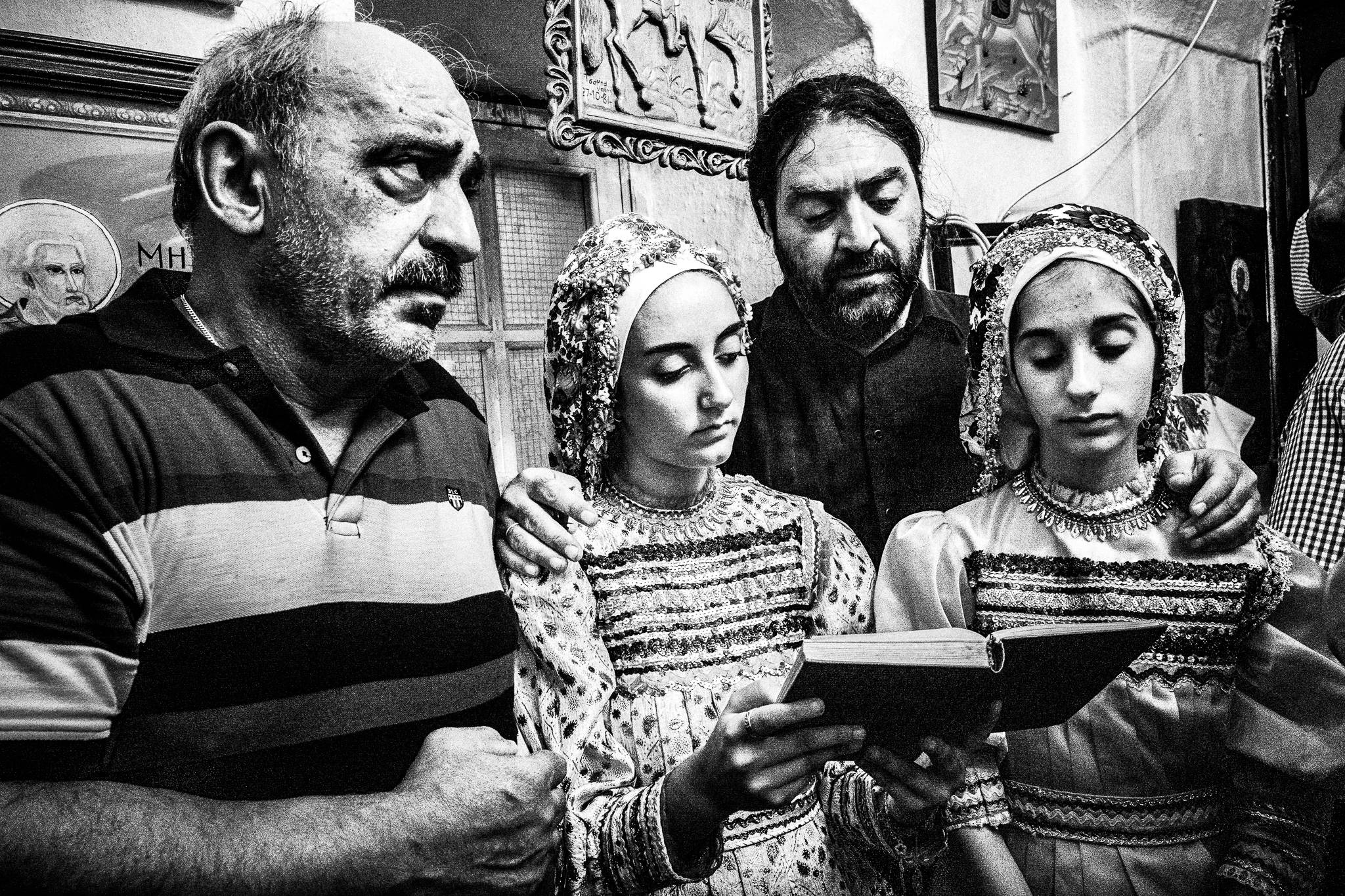 Chanting in the church during a traditional baptism in St. Minas, Olympos, Karpathos, Greece. Black and white photography by George Tatakis
