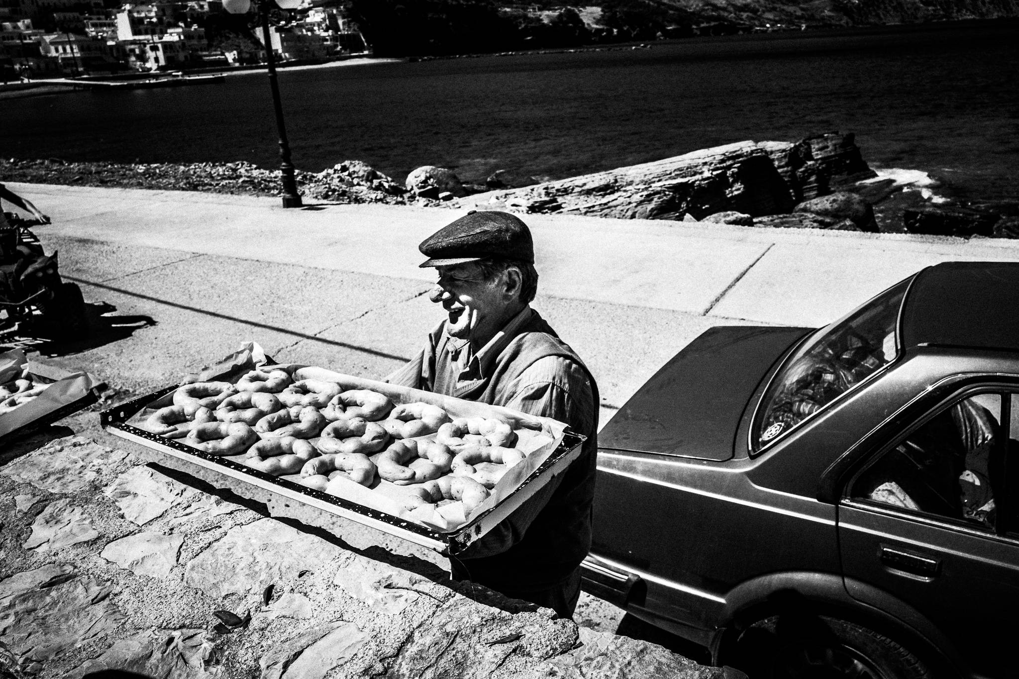 An elderly man, taking a tray of Easter bread out of the trunk. Diafani, Karpathos, Greece
