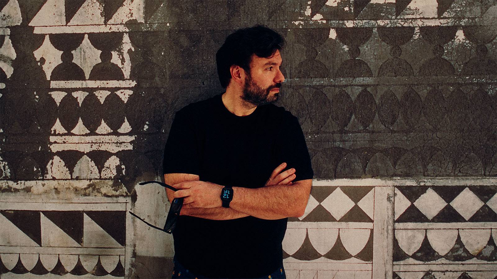 George Tatakis standing in front of the geometric wall in Pyrgi, Chios, where one of the Caryatis photographs was made.