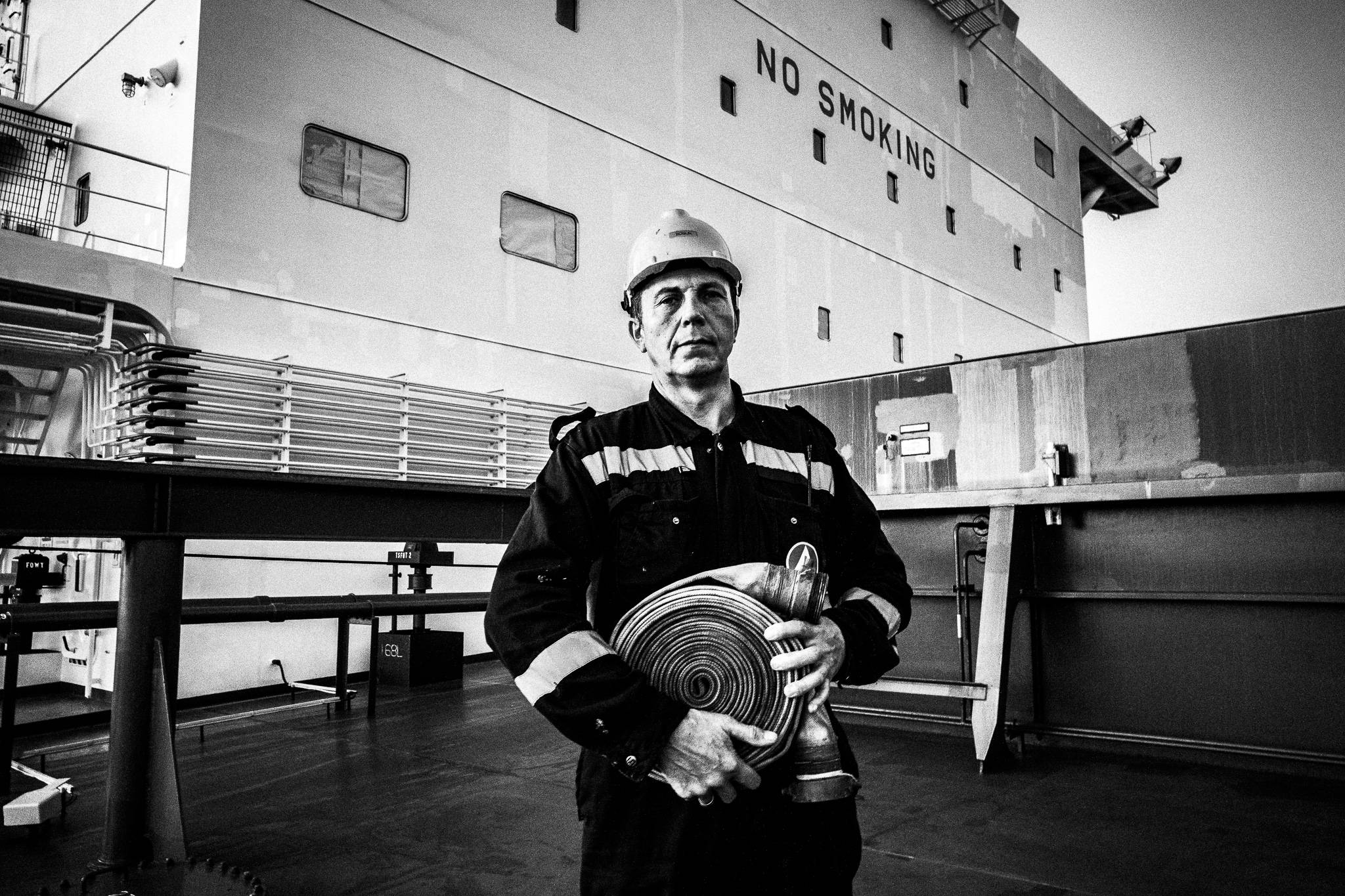 Bosun on deck holding a water hose by photographer George Tatakis