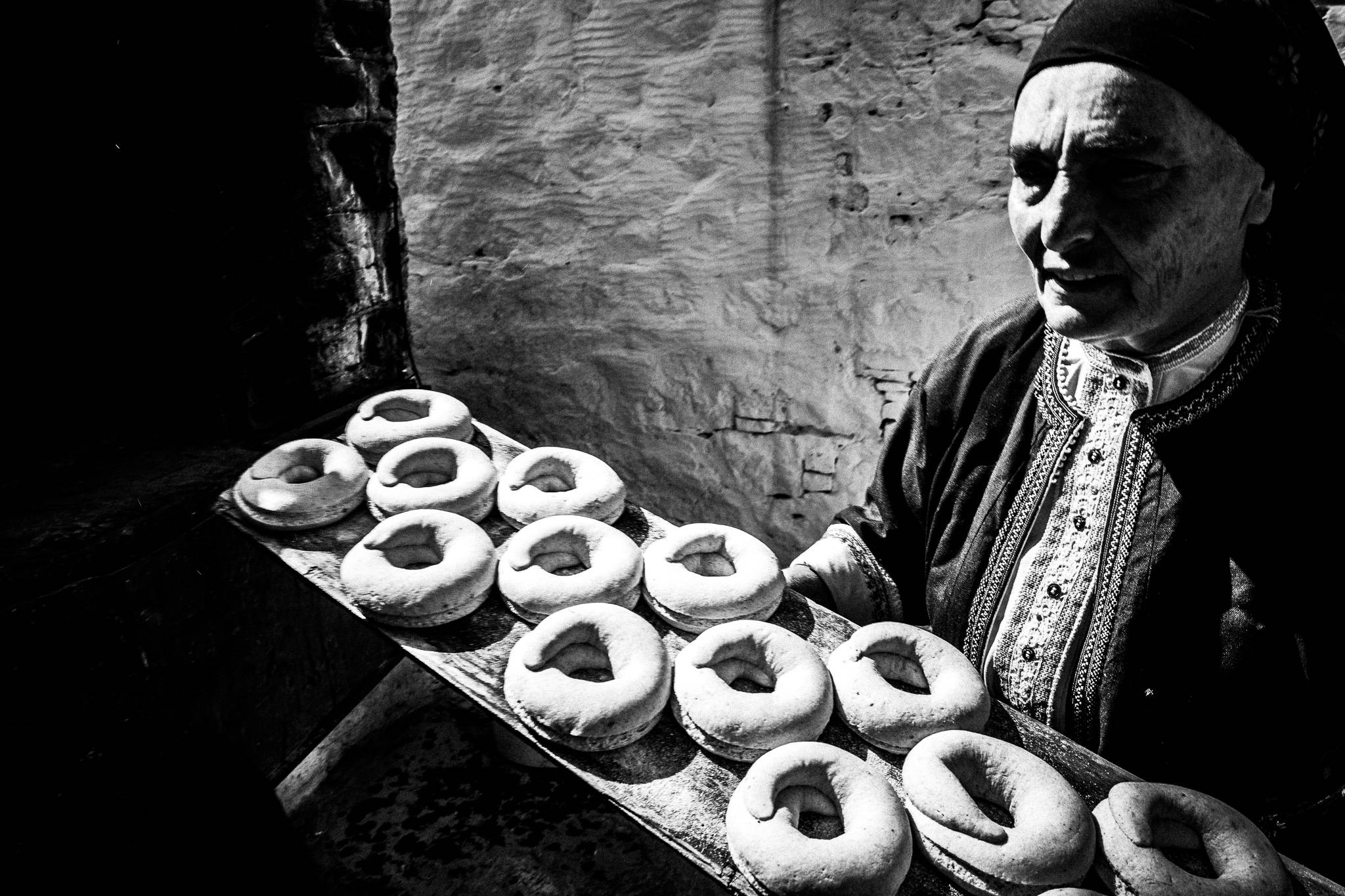 A woman in the traditional costume, holding a tray of Easter rusks at Mylos tavern, Olympos, Karpathos, Greece