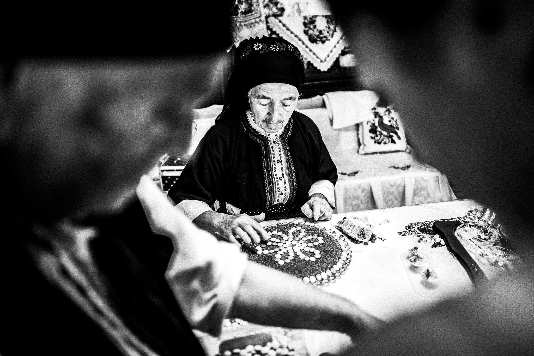 Papa Yannis’ wife Irene, decorating a local confection with sesame and honey. Olympos, Karpathos, Greece. Black and white photography by George Tatakis