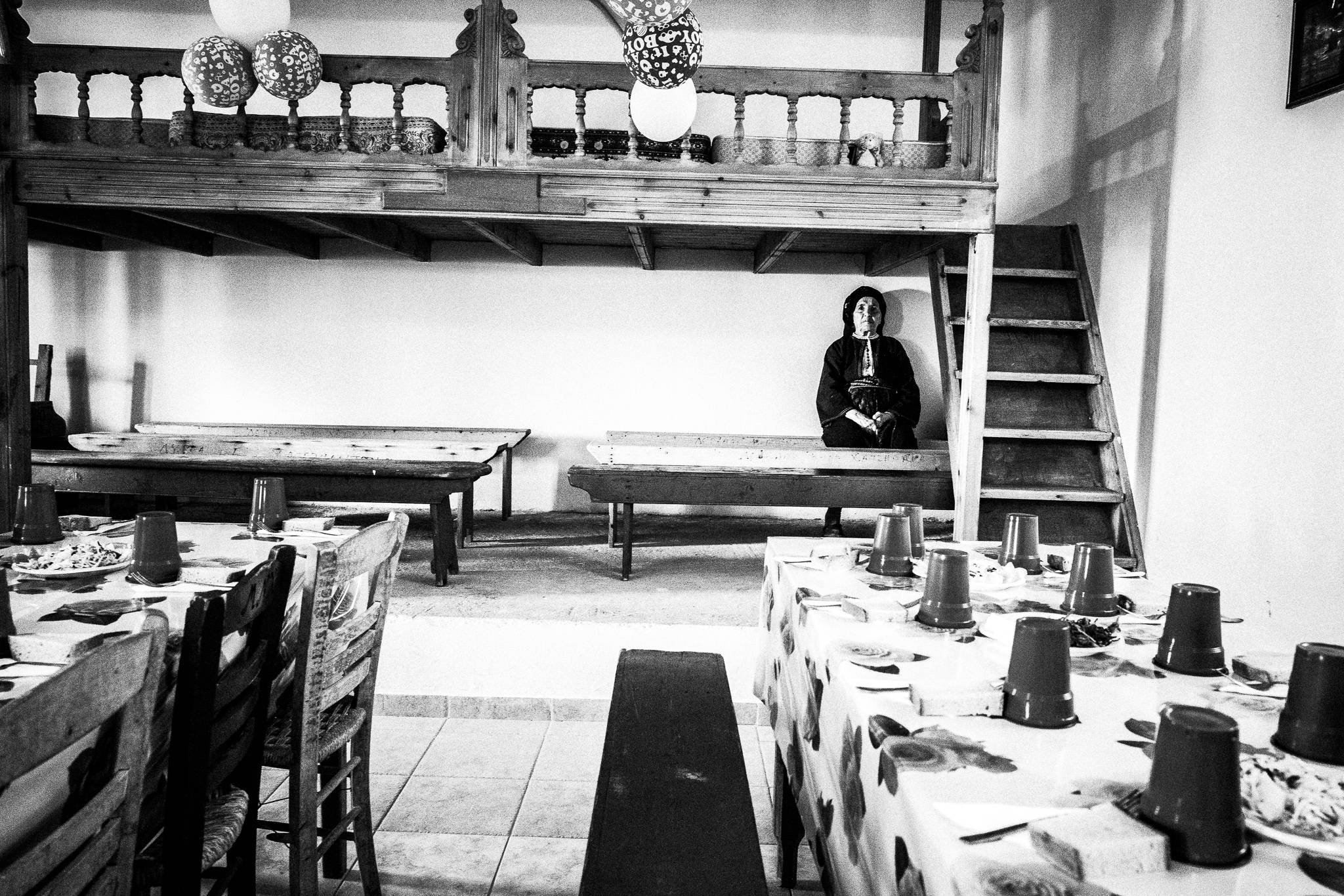 Inside the megaron at a traditional baptism in St. Minas, Olympos, Karpathos, Greece. Black and white photography by George Tatakis