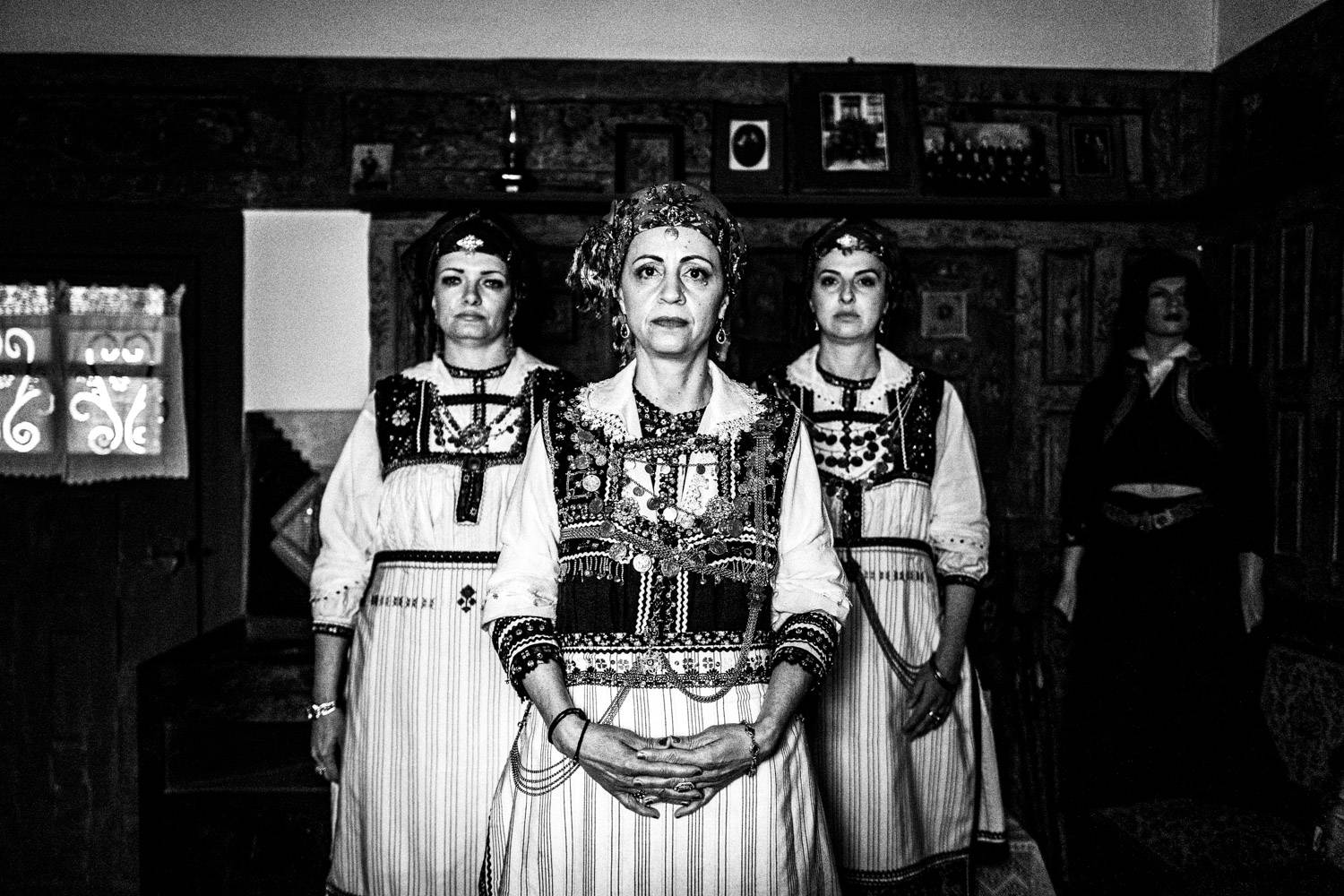 Three women inside a Mansion in Siatista, wearing the local attire of Tsartsampas. Macedonia, Greece. Black and white photograph by George Tatakis