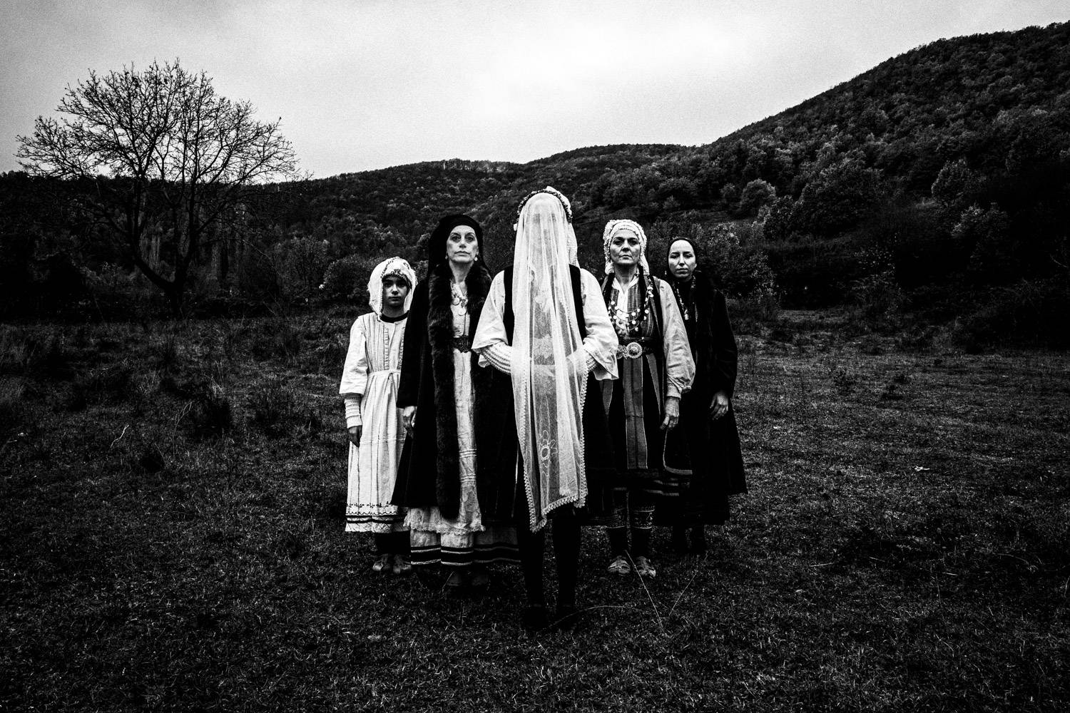 Portrait of five women in an arrow formation at a local valley, wearing the folklore dresses. Ermakia, Ptolemaida, Macedonia, Greece. Black and white photograph by George Tatakis