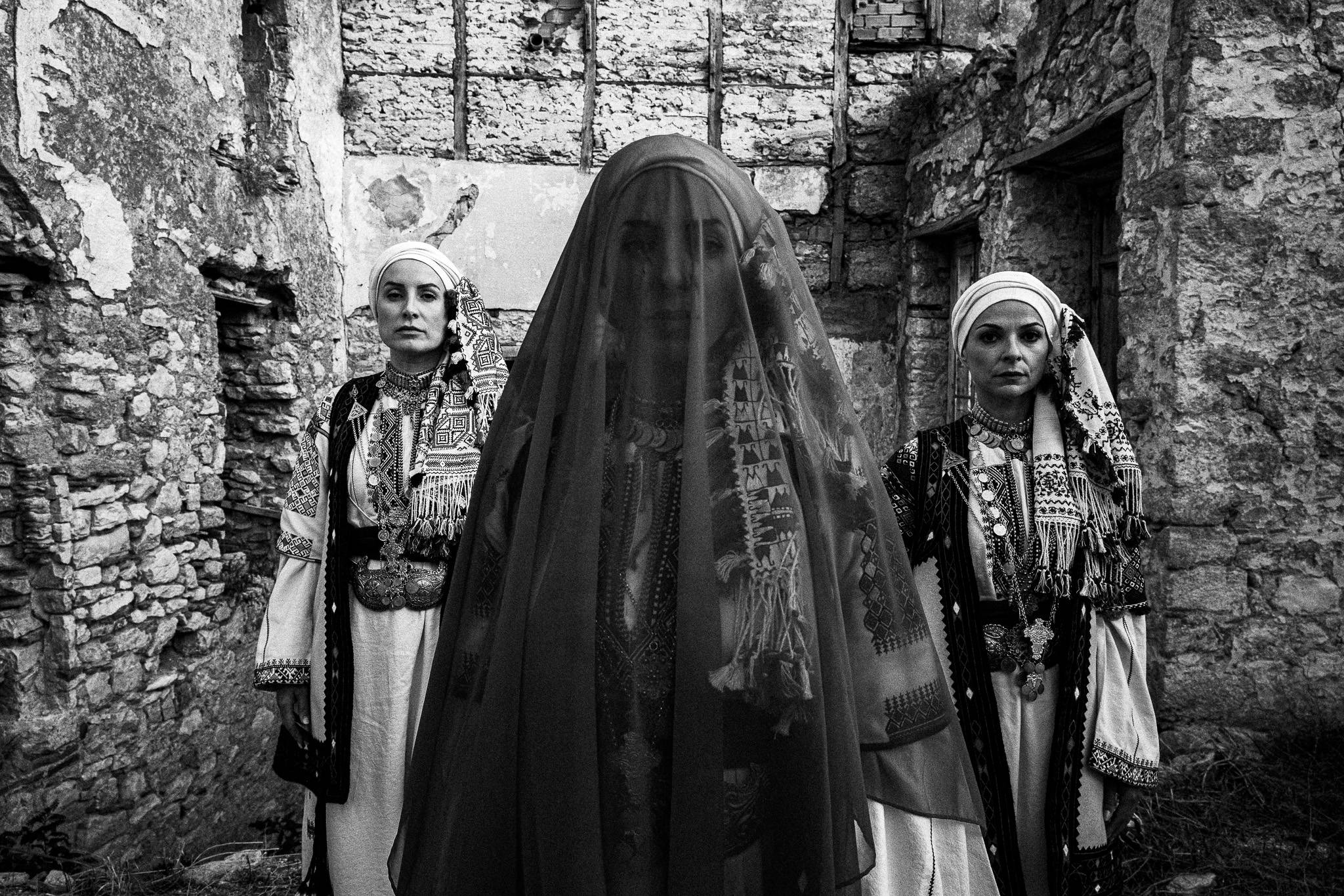Three women wearing the local costumes of Kyparissia, in Peloponnese, Greece. The woman the front is veiled.