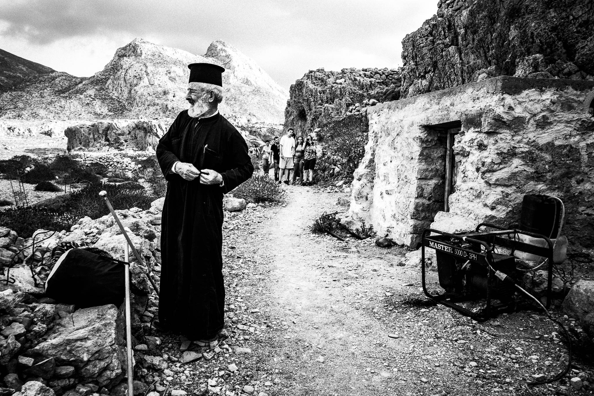 Putting on vestments during the feast of Saint John at the site of the ancient city of Brykous, Olympos, Karpathos, Greece. Black and white photography by George Tatakis