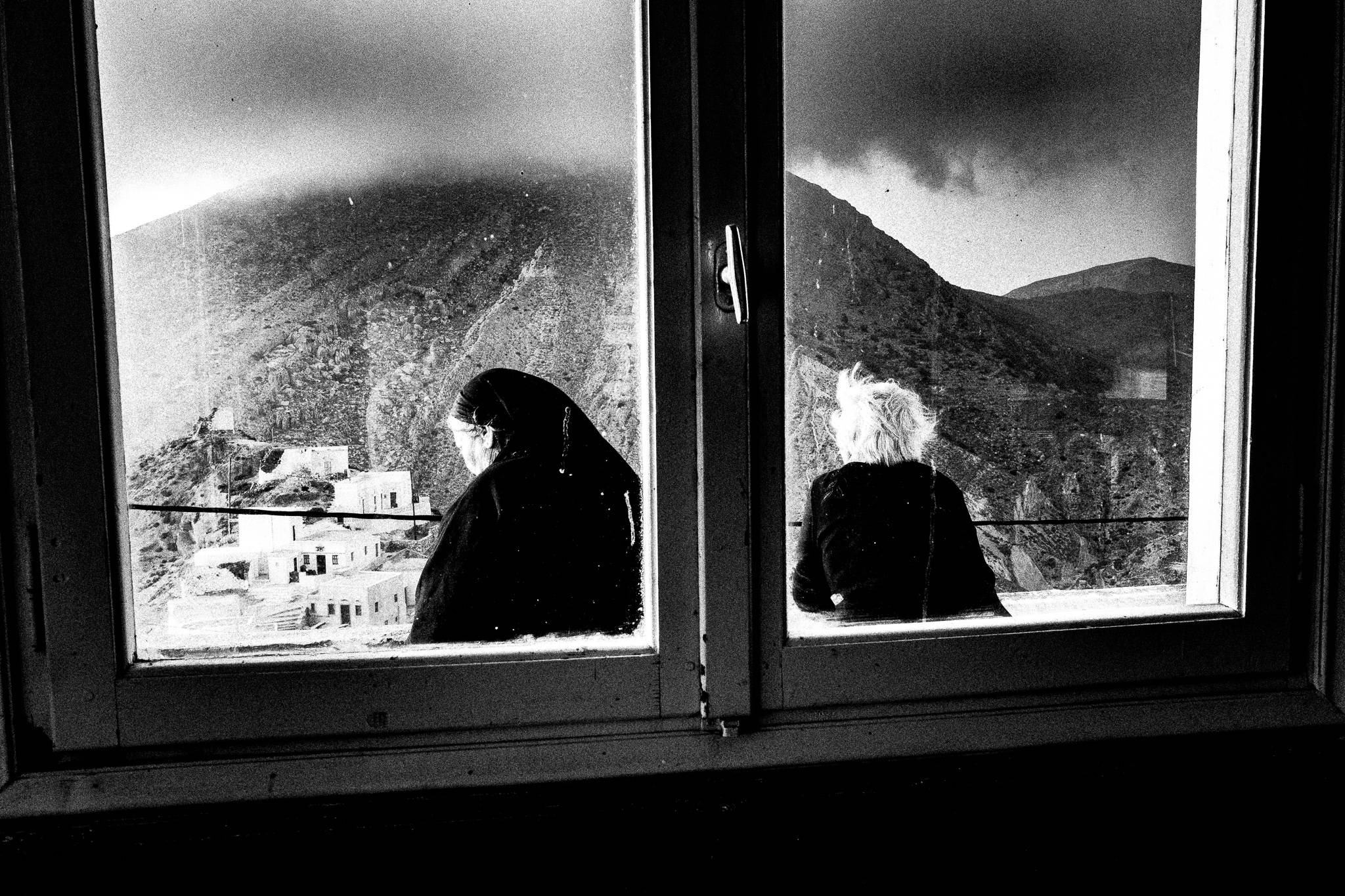 Archontoula with her best friend outside the megaron in Olympos, Karpathos, Greece. Black and white photography by George Tatakis