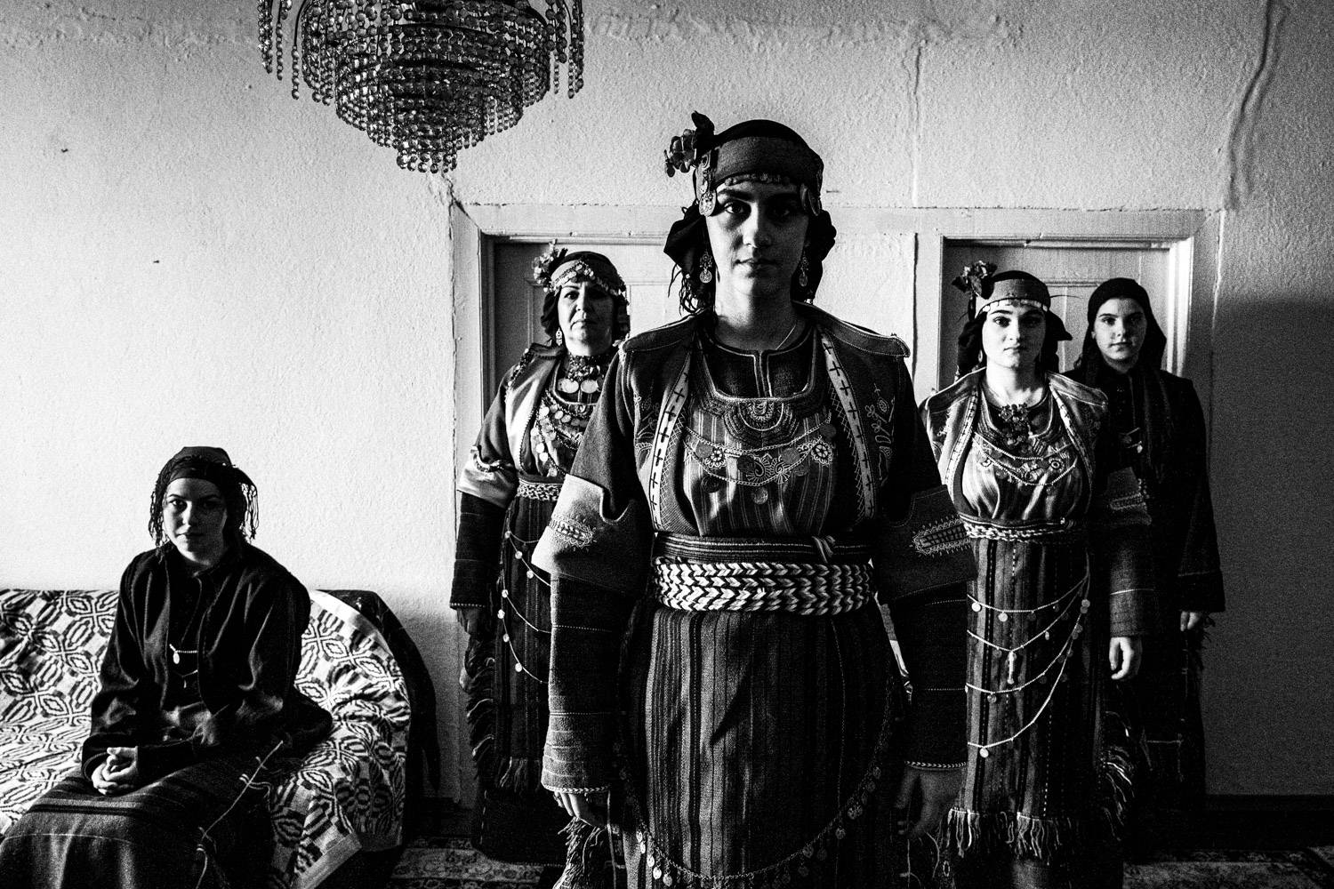 Portrait of five women inside a local traditional home, wearing the folklore dresses. Drymos, Thessaloniki, Macedonia, Greece. Black and white photograph by George Tatakis