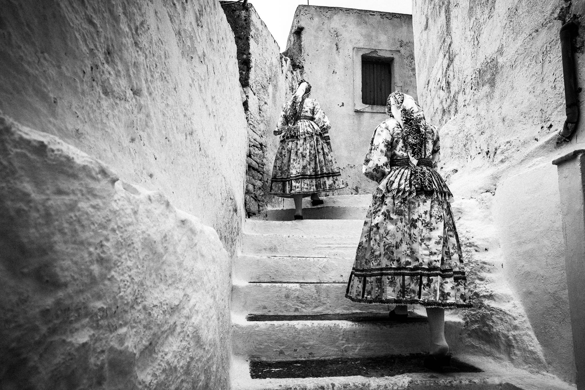 Girls approaching the church in Olympos, Karpathos, Greece. Black and white photography by George Tatakis