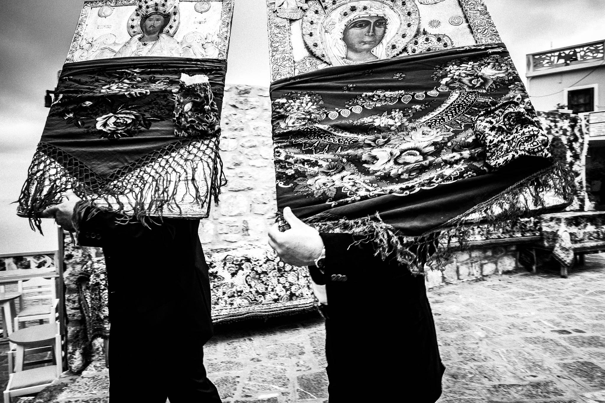 Carrying two heavy wooden Orthodox Icons, across the main square of Olympos, Karpathos, Greece.