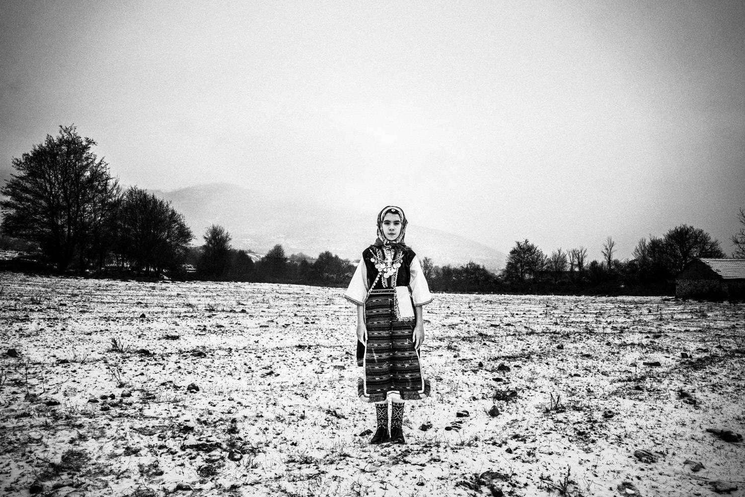 A girl in the snow in Volax, Macedonia, Greece. Black and white photograph by George Tatakis