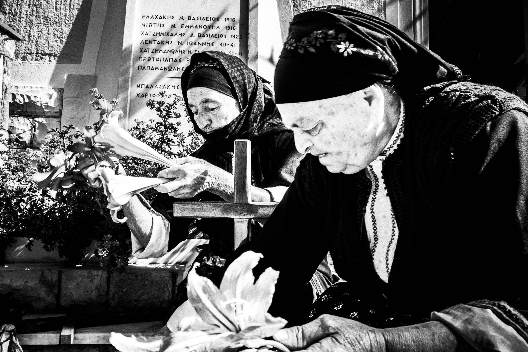 Two elderly women in their traditional costumes, decorating wooden crossed with Lillium. Olympos, Karpathos, Greece
