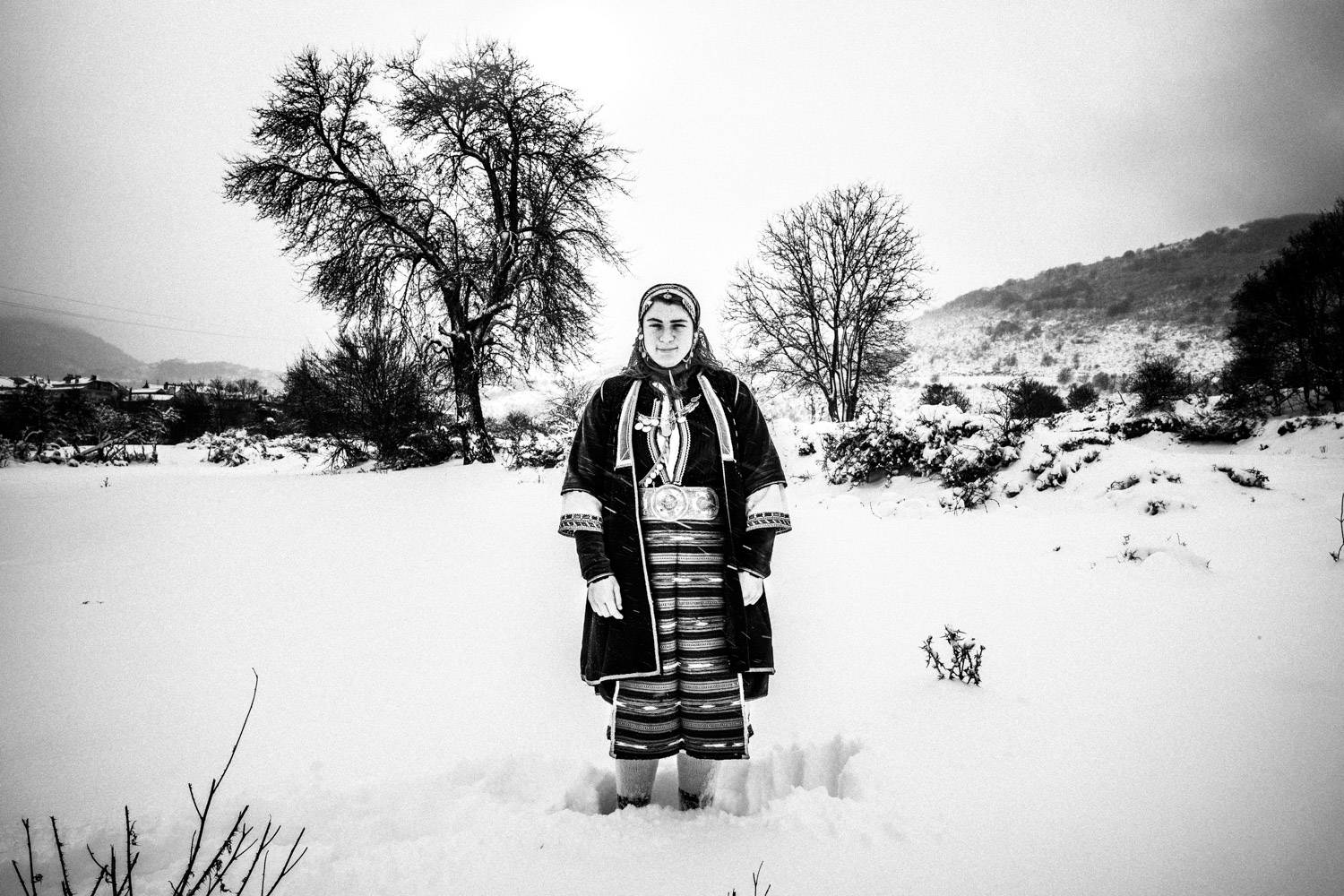 An Olympic athlete wearing the folklore dress of Volax in the snow, Macedonia, Greece. Black and white photograph by George Tatakis
