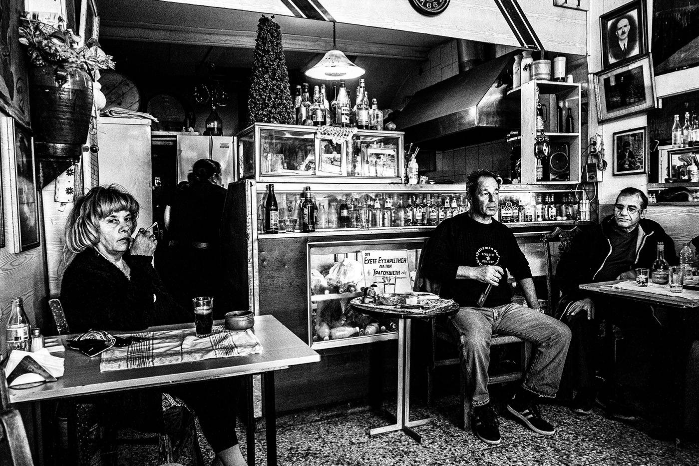 Ο τραγουδιστής στο καφενείο Θεόκλητος - Ένα κρυμμένο στολίδι στον Πειραιά, Ελλάδα. Ασπρόμαυρη φωτογραφία του Γιώργου Τατάκη