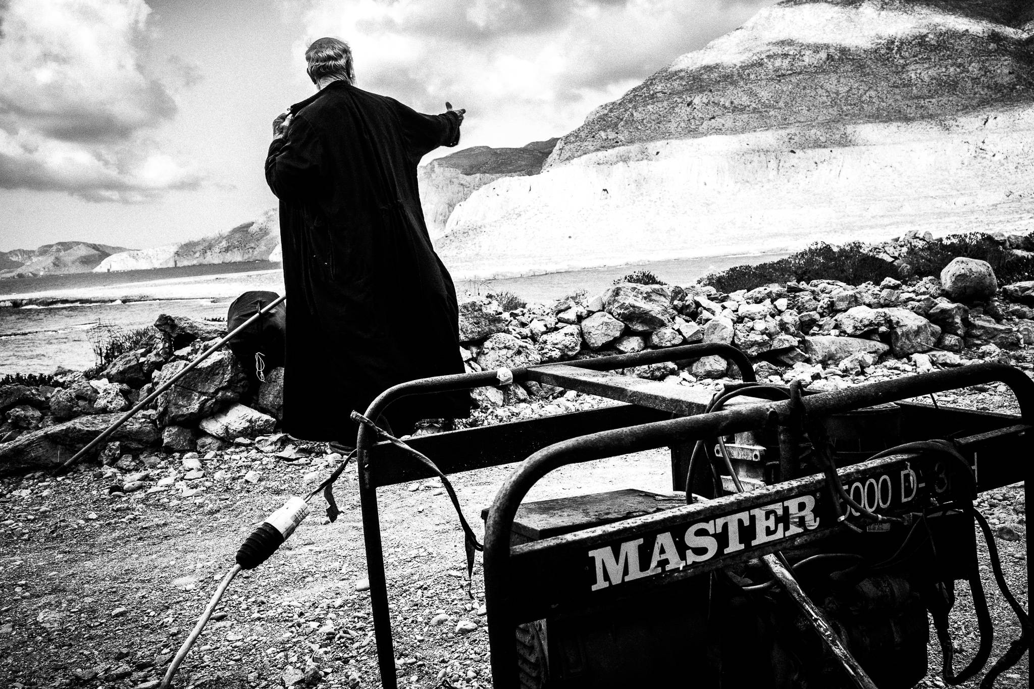Papa-Yannis wears his vestments a few hundrer meters before reaching the celebration spot at the ancient city of Brykous, Olympos, Karpathos, Greece. Black and white photography by George Tatakis