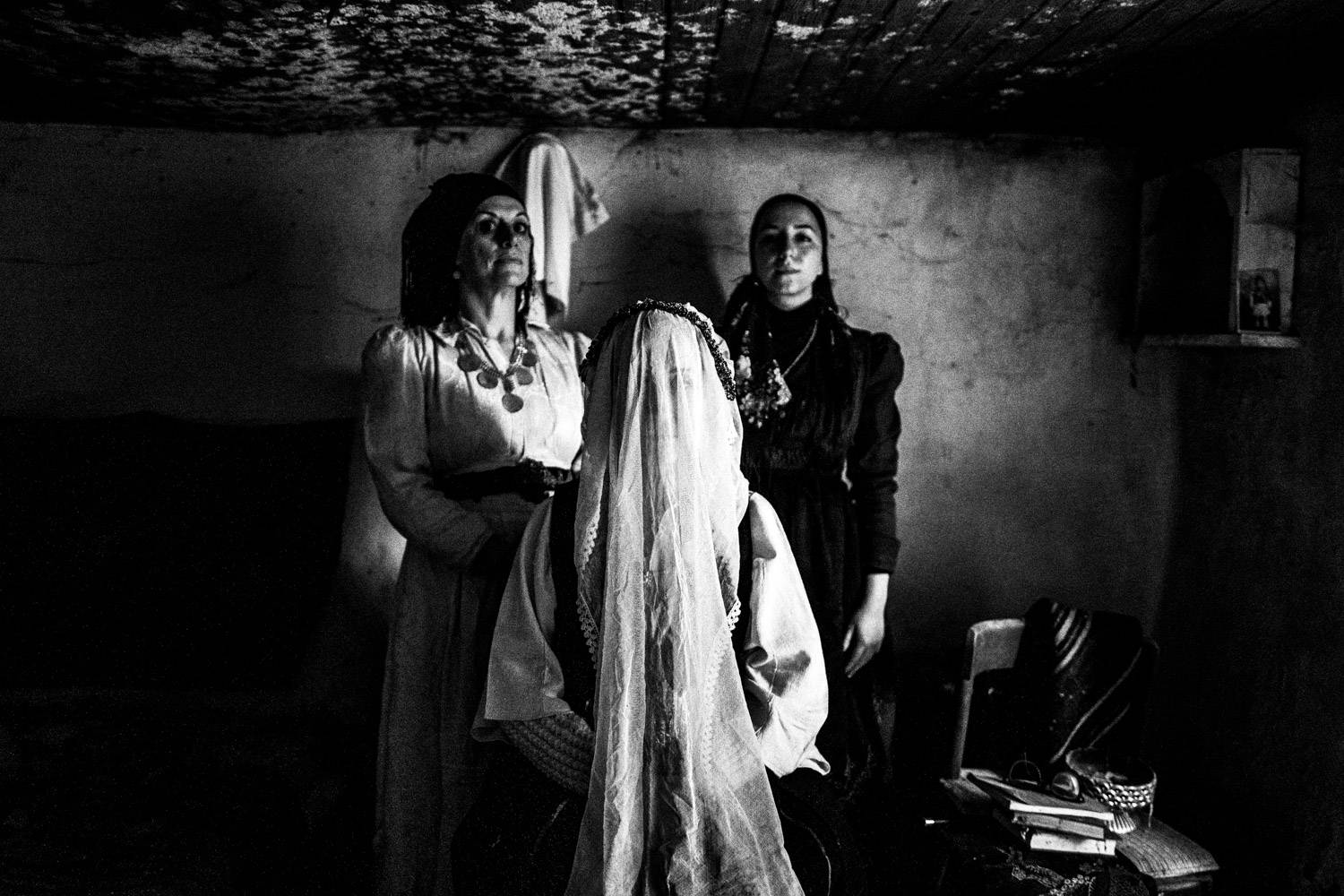 Portrait of three women wearing the local folklore dresses, at an abandoned house. Ermakia, Ptolemaida, Macedonia, Greece. Black and white photograph by George Tatakis