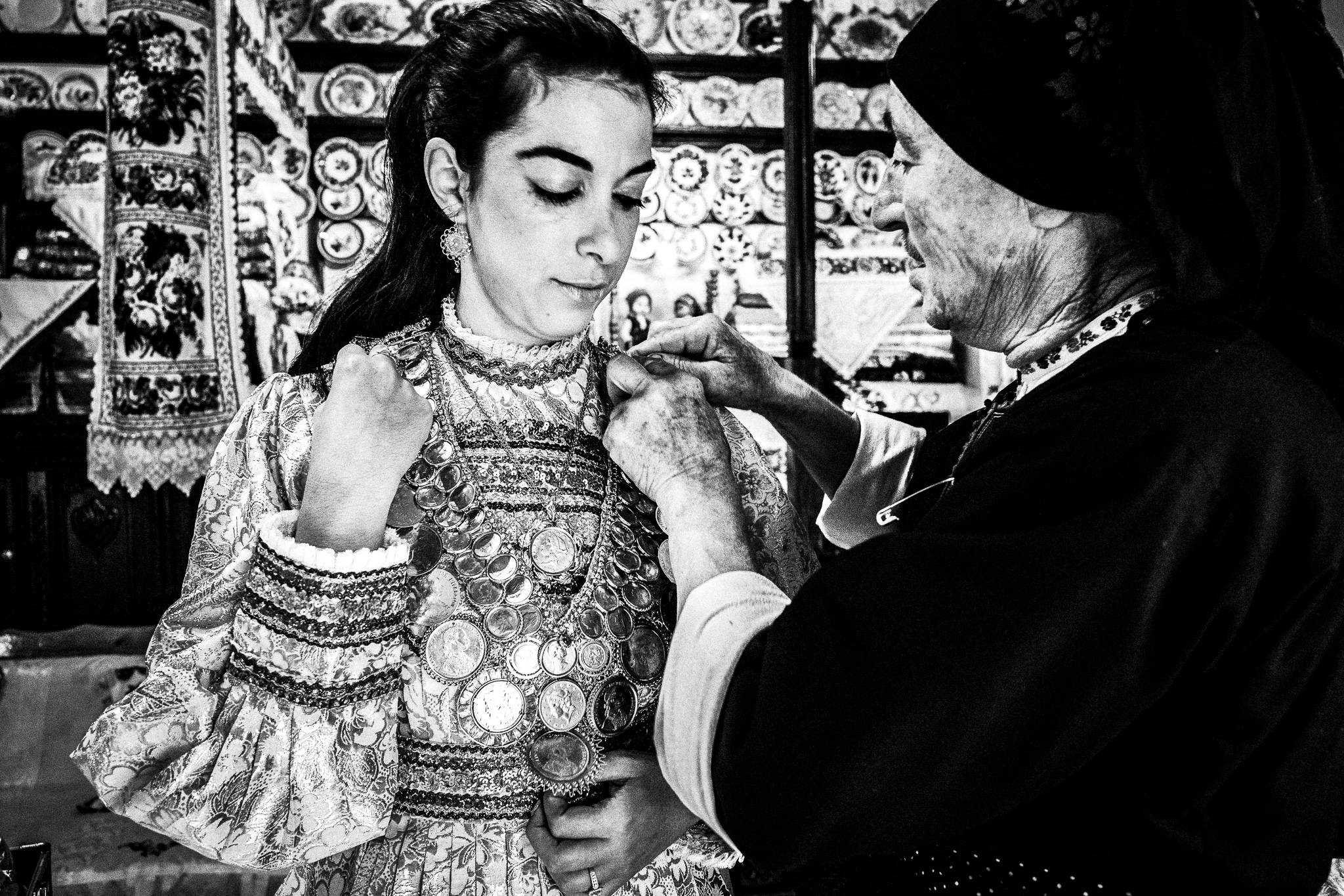 The bride-to-be gets help with her dress in Olympos, Karpathos, Greece. Black and white photography by George Tatakis