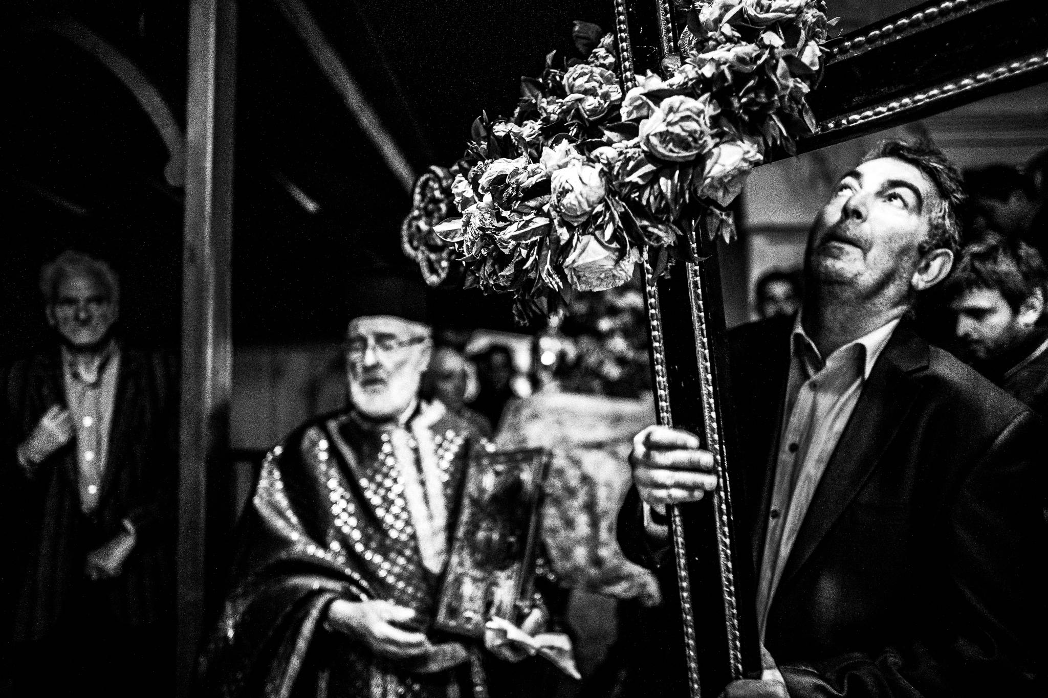 A man carrying a large wooden cross during the procession of the Epitaphios. Olympos, Karpathos, Greece