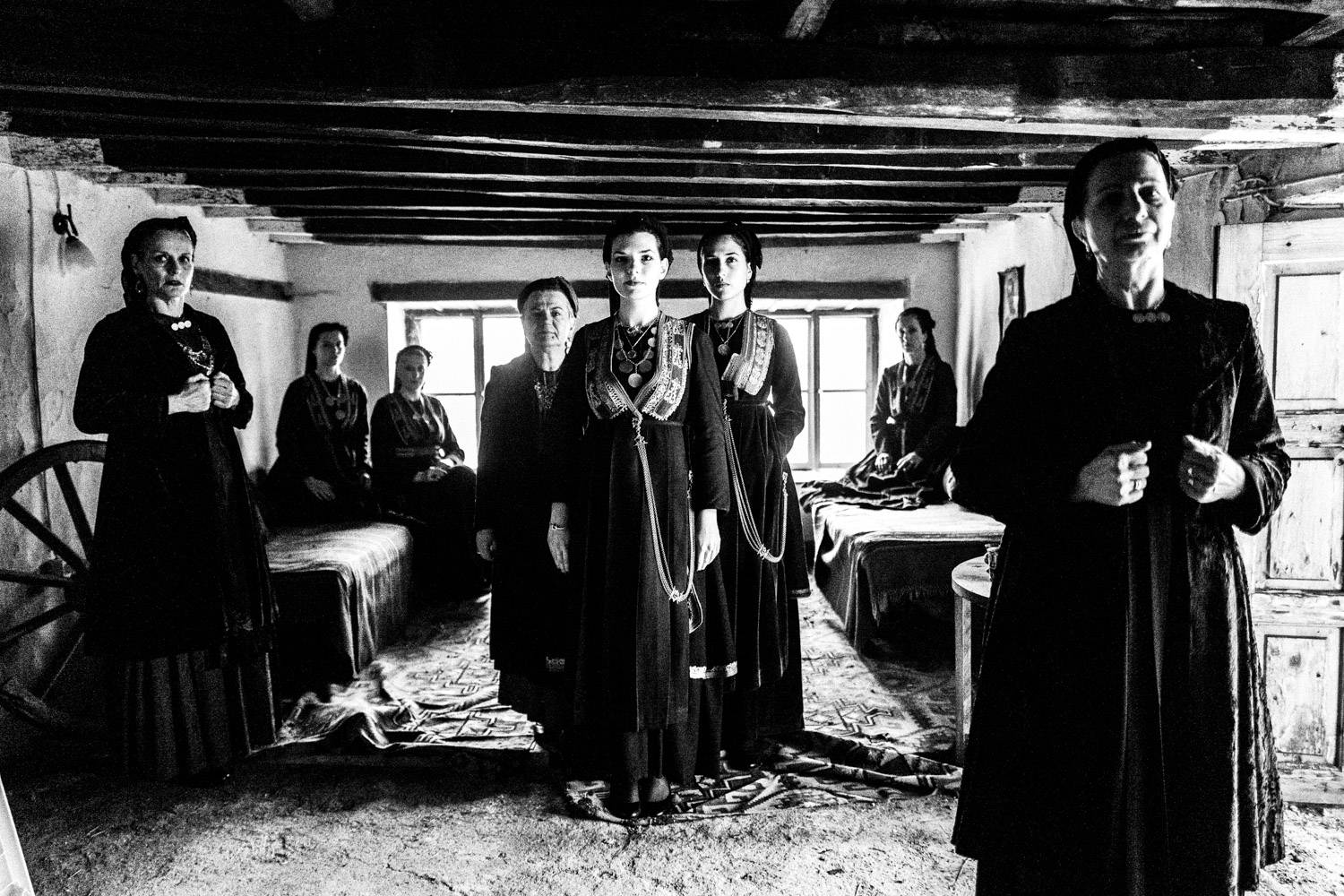 A group of women inside a local abandoned house, wearing the Vlach folklore dresses. Seli, Imathia, Macedonia, Greece. Black and white photograph by George Tatakis