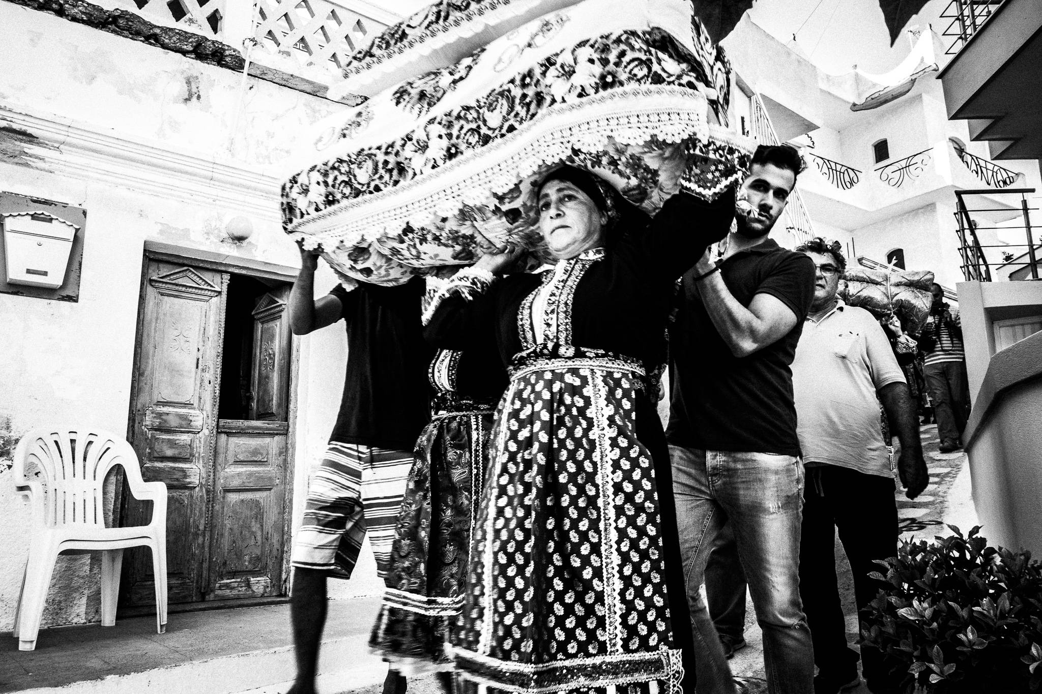 The dowry Reaching the bride's house at a wedding in Olympos, Karpathos, Greece. Black and white photography by George Tatakis