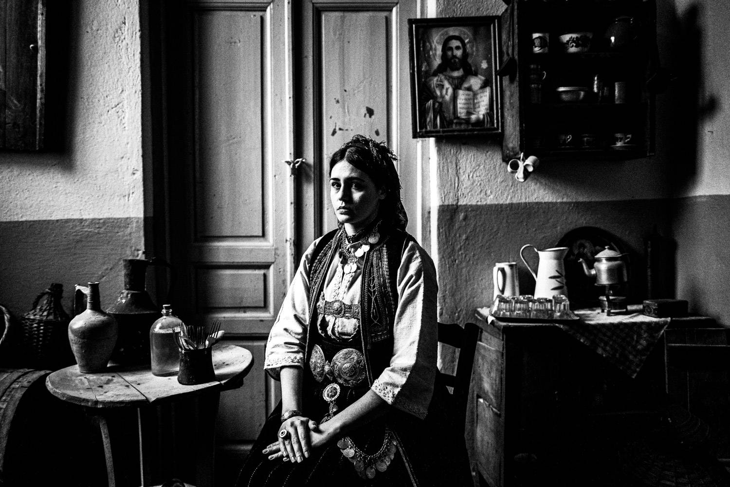 Sitting portrait of a woman at the local folklore museum, wearing the traditional outfit. Polypotamos, Florina, Macedonia, Greece. Black and white photograph by George Tatakis