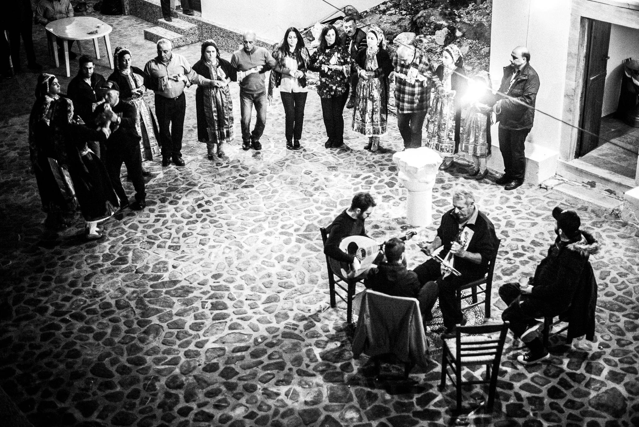Dancing the pano choros in the church courtyard at the festival of Michael the Archangel at Tristomo, Olympos, Karpathos, Greece. Black and white photography by George Tatakis