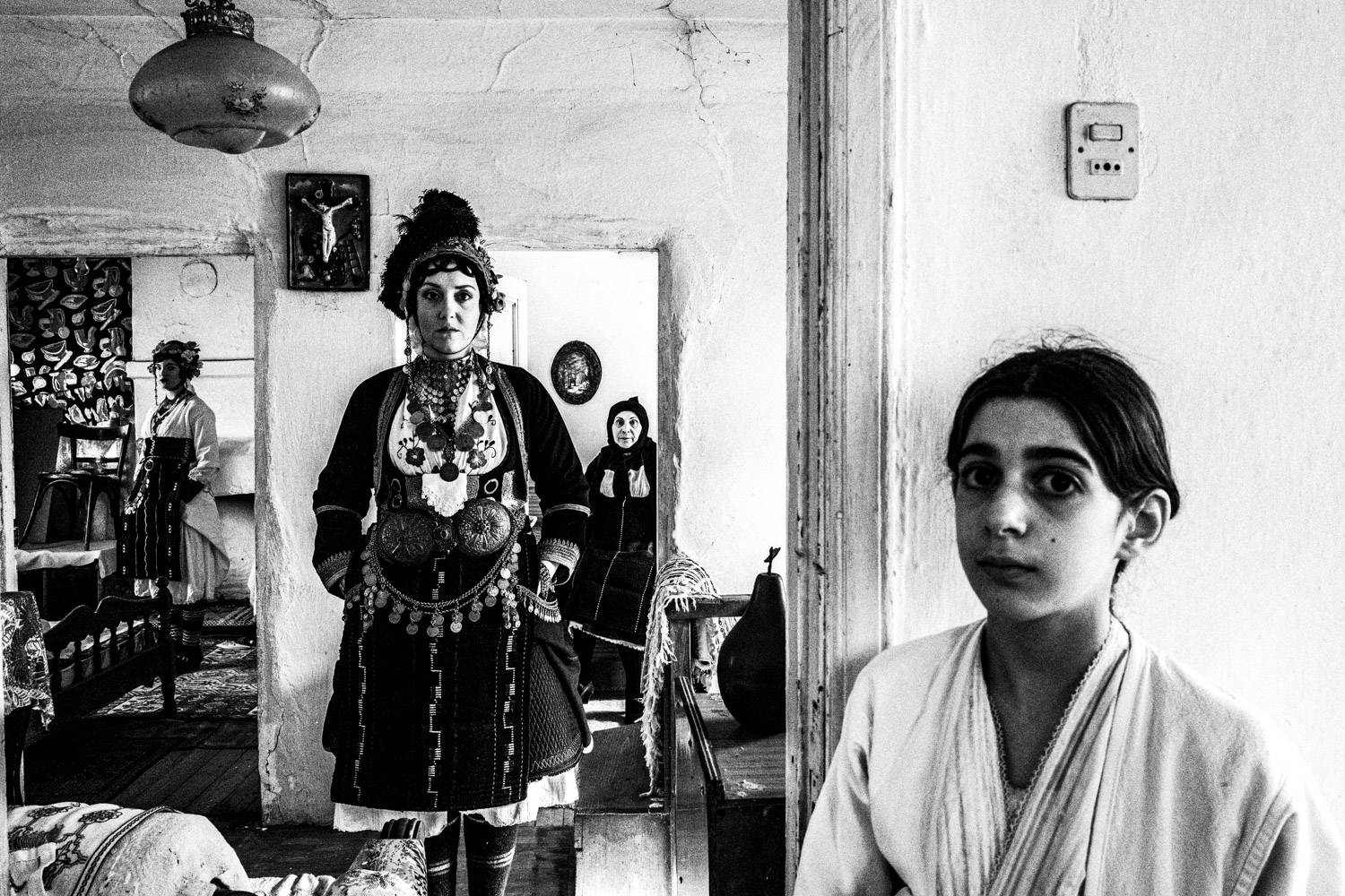 A group of women wearing the Roumlouki folklore dresses, inside a local traditional home. Meliki, Imathia, Macedonia, Greece. Black and white photograph by George Tatakis