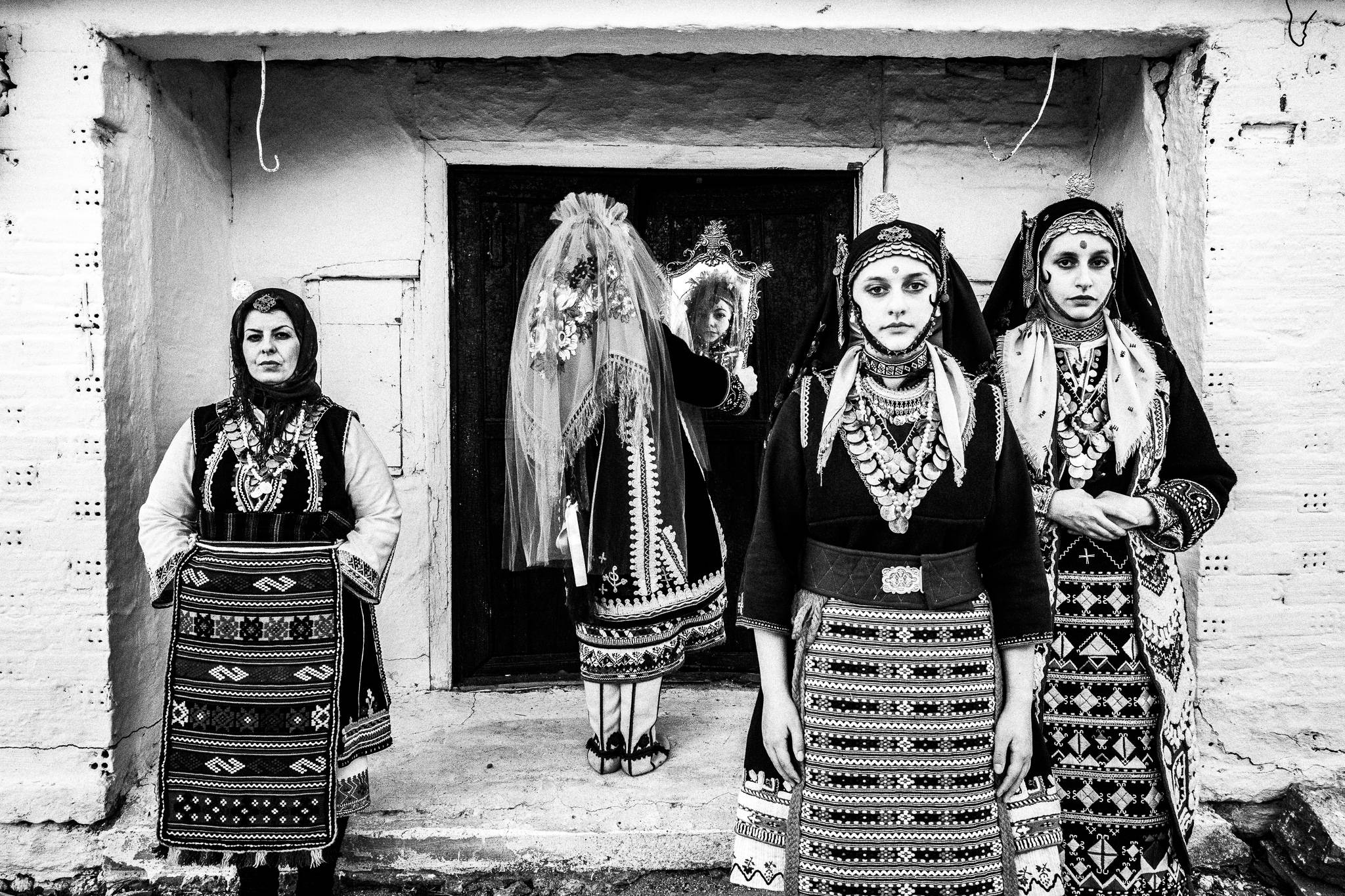 The bride looking herself in the mirror with bridesmaids and mother-in-law at Issaakion, Evros, Thrace, Greece, by photographer George Tatakis