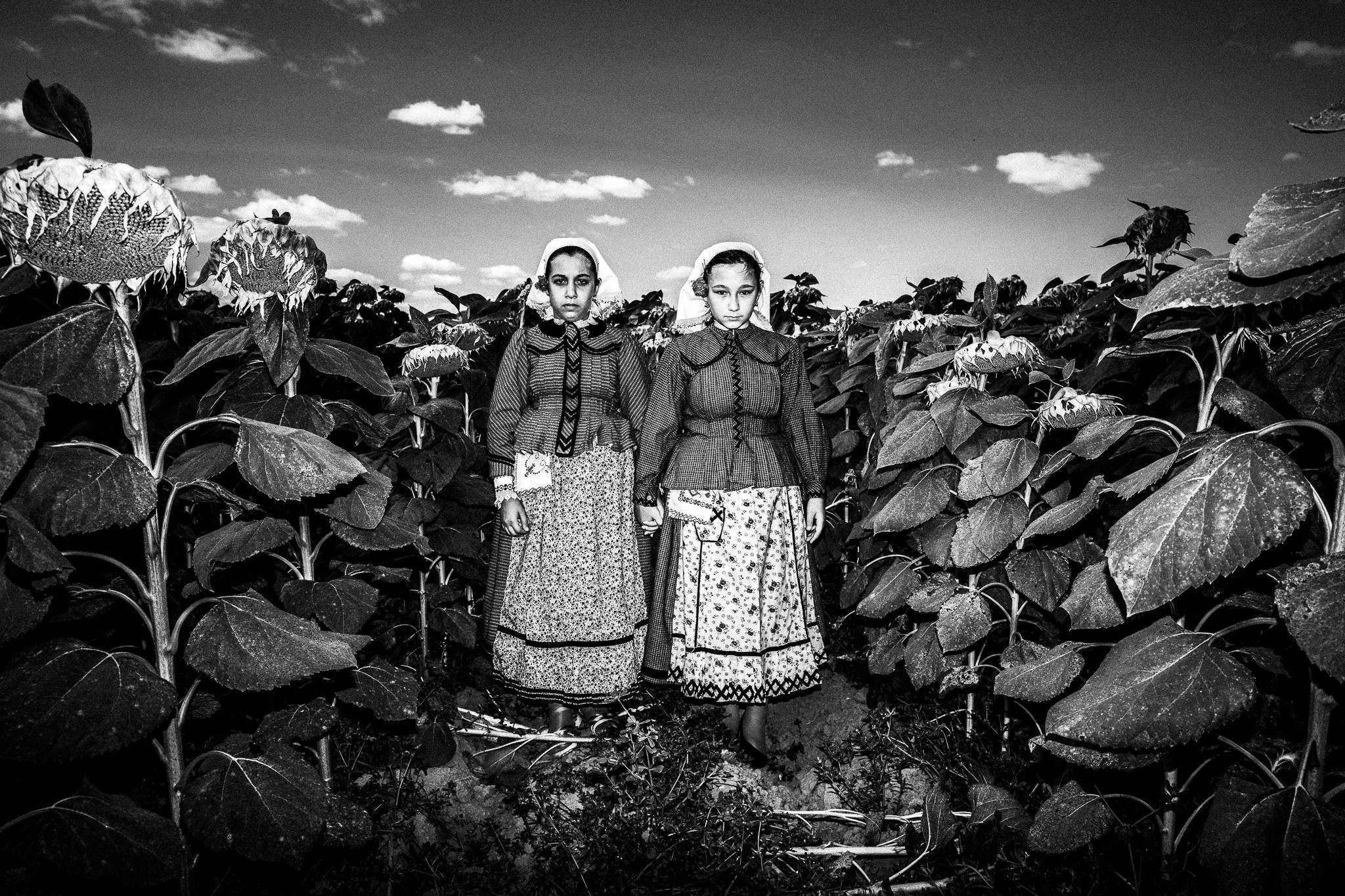 Two girls in the traditional attire at a sunflower field, by photographer George Tatakis