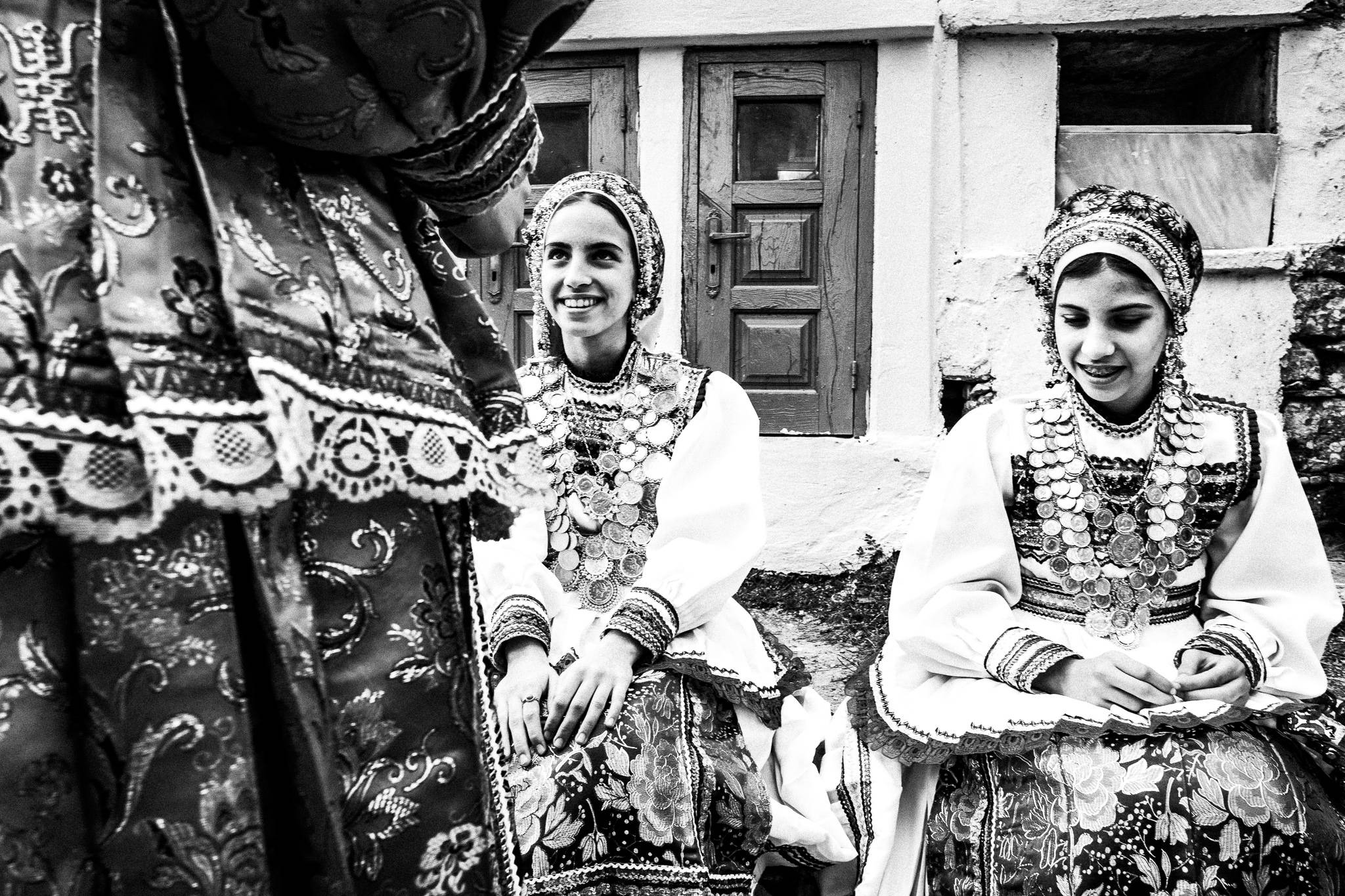 Young girls in their traditional costumes, smiling at the local cemetery. Olympos, Karpathos, Greece. 