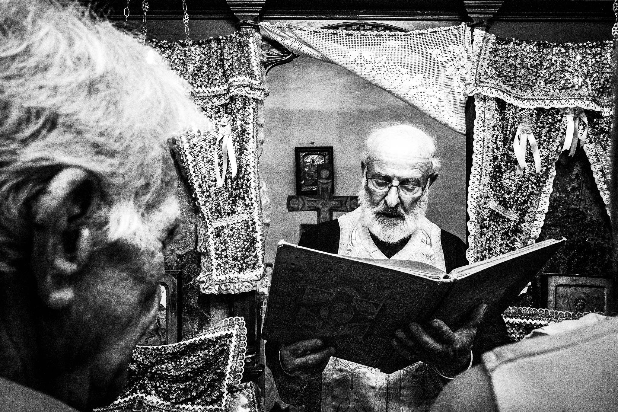 The prist performing a traditional baptism in St. Minas, Olympos, Karpathos, Greece. Black and white photography by George Tatakis