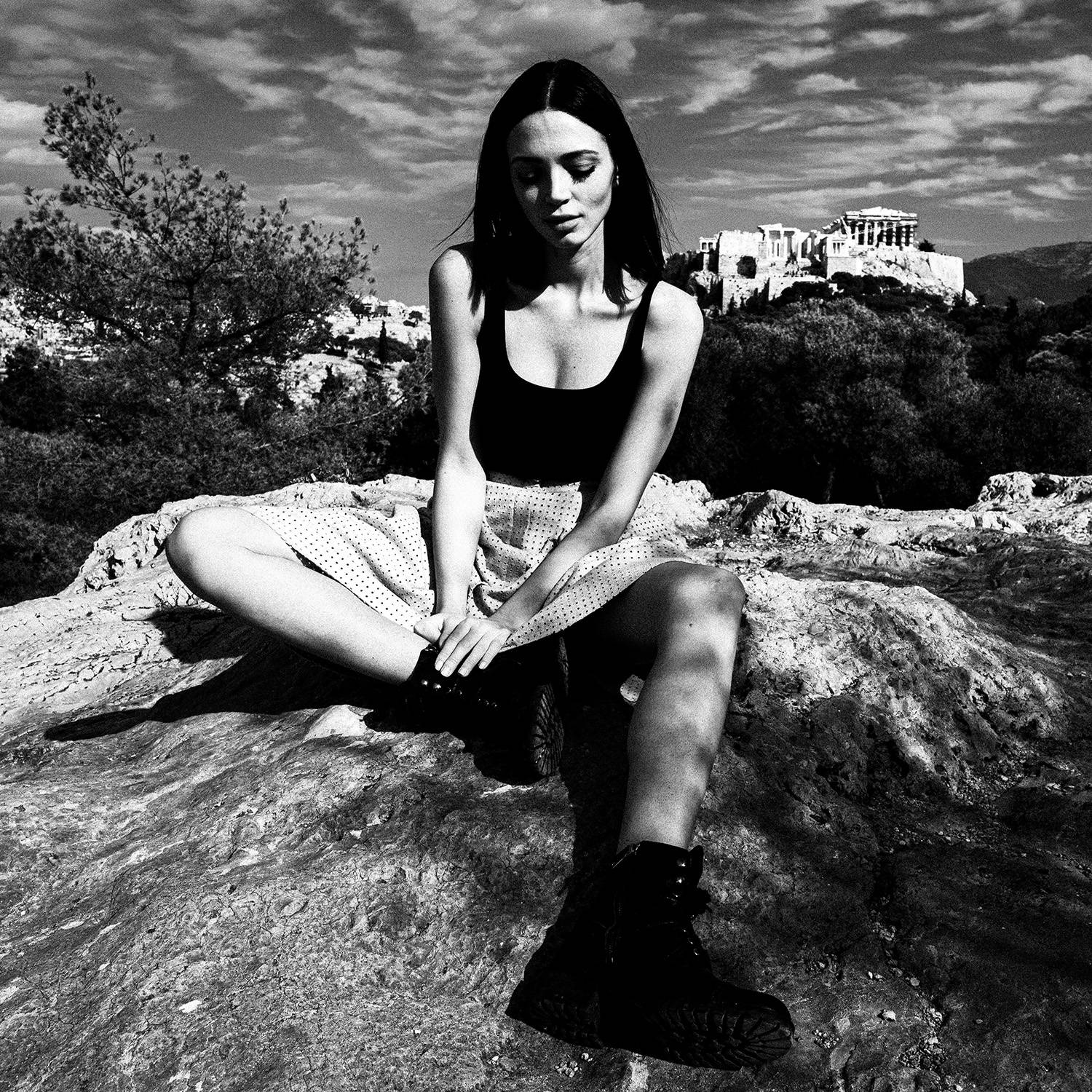 Black and white photograph of a model posing against the Acropolis in Athens, Greece