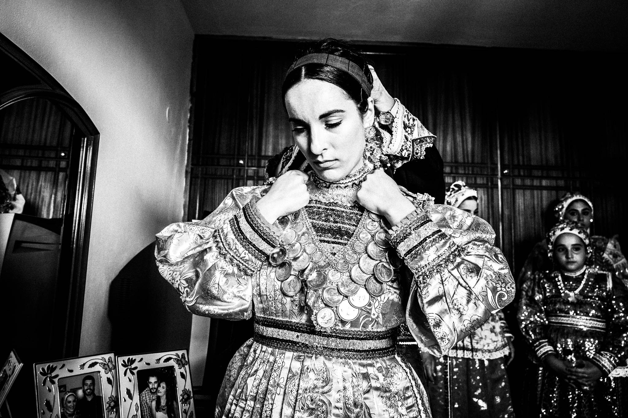 Putting on the Kolaina at a traditional wedding at Olympos, Karpathos, Greece. Black and white photography by George Tatakis