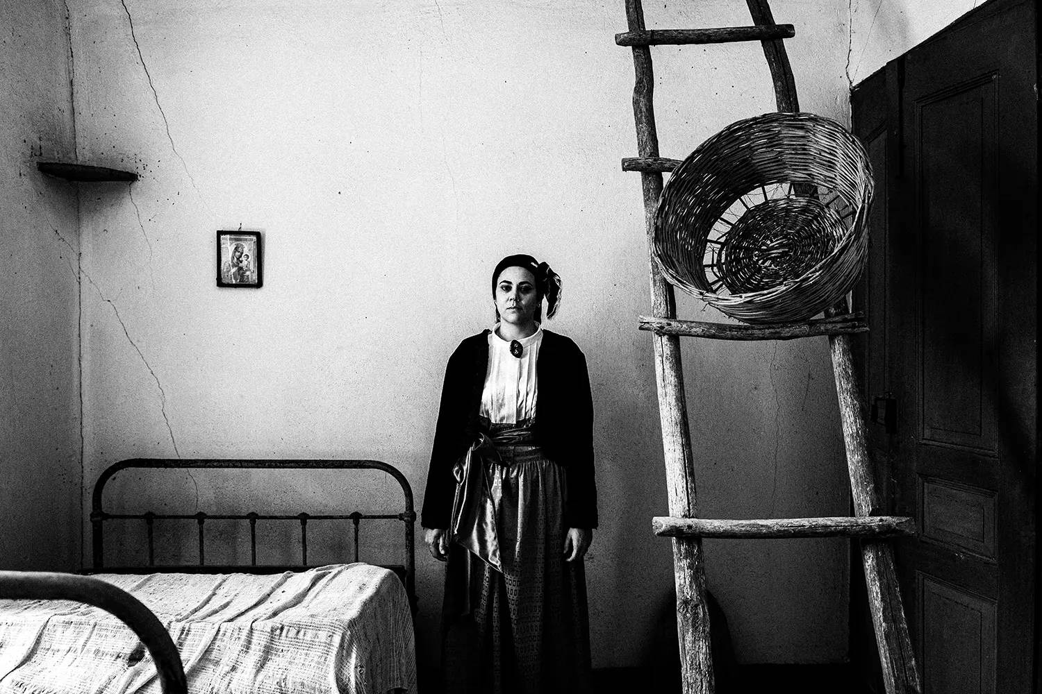 A woman posing next to a wooden ladder, wearing the local urban dress of Pelion, Thessaly, Greece. Black and white photography by George Tatakis