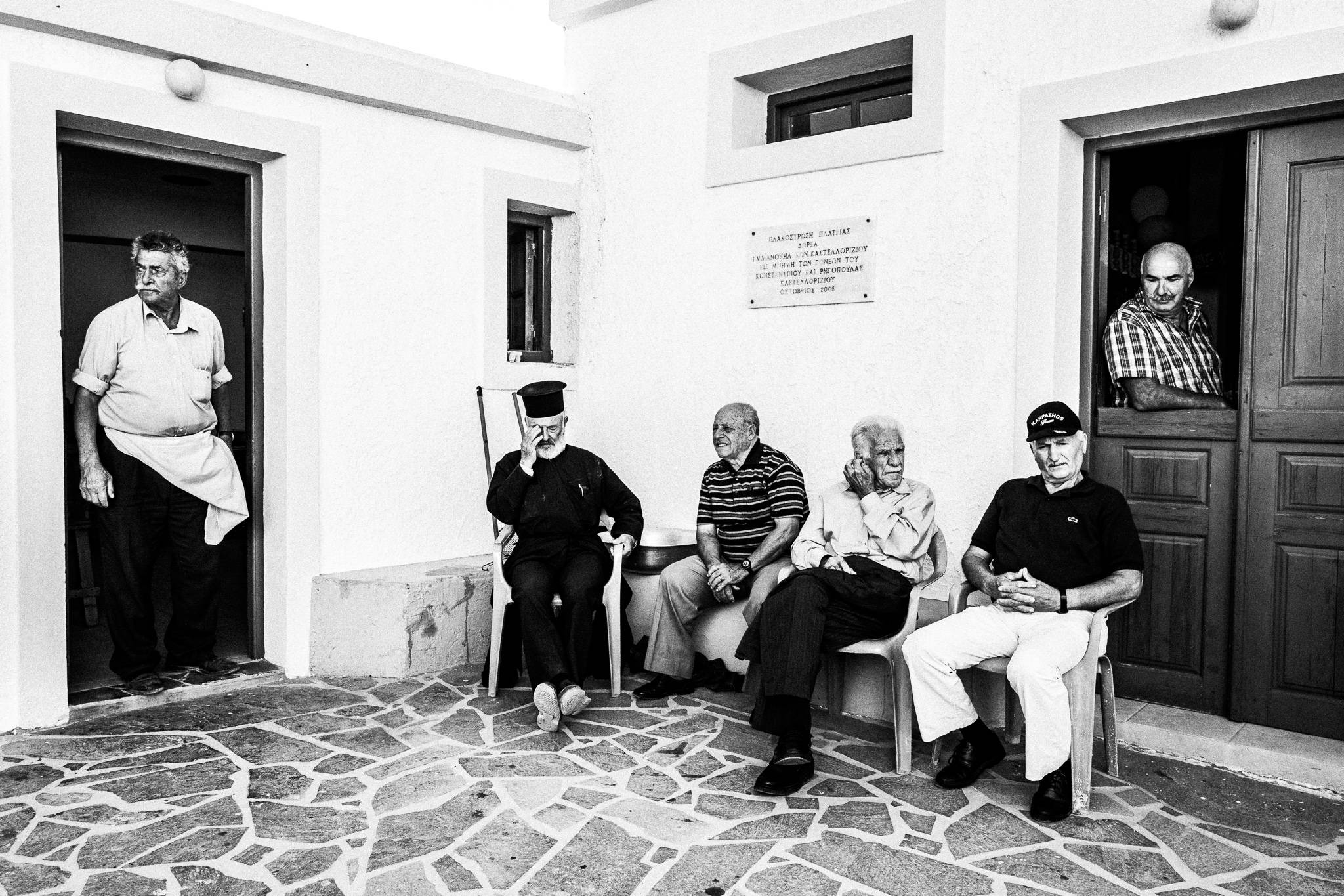 The cook, priest and friends at a traditional baptism in St. Minas, Olympos, Karpathos, Greece. Black and white photography by George Tatakis